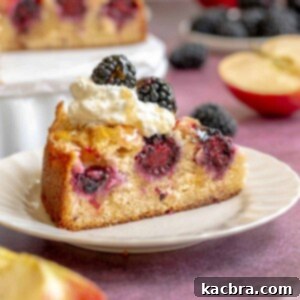 A slice of blackberry apple cake on a plate with whipped cream on top.