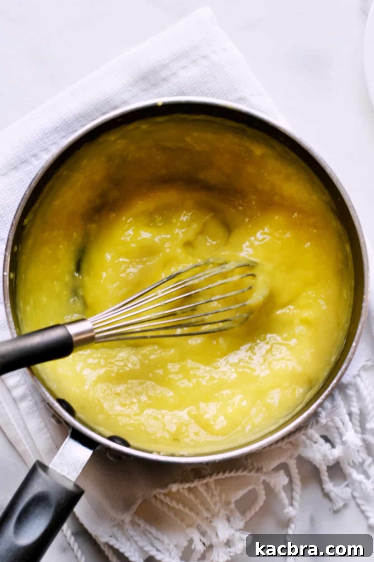 The lemon curd mixture in the saucepan, now visibly thickened and creamy, indicating it has been cooked to the perfect consistency.