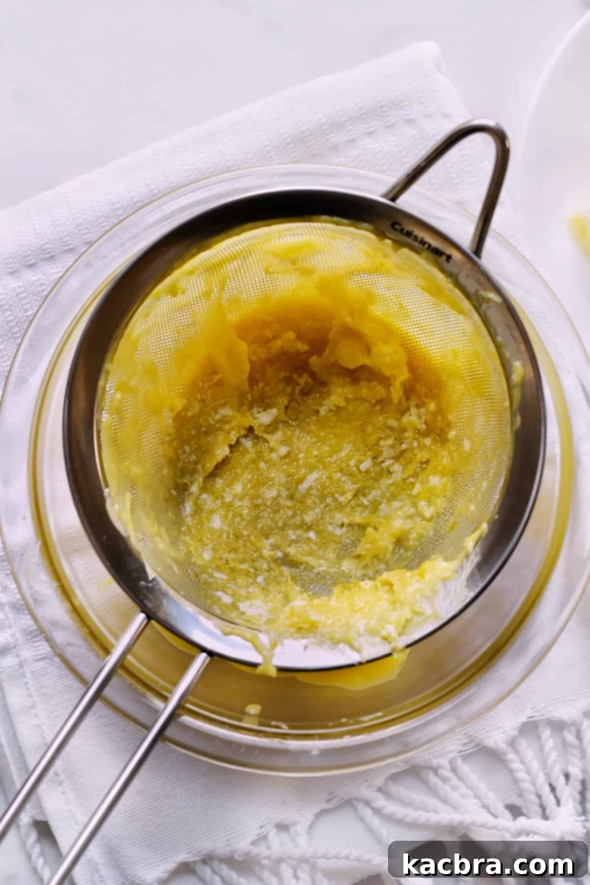 Cooked egg pieces and residual lemon zest collected within a fine mesh sieve after the lemon curd has been expertly strained.