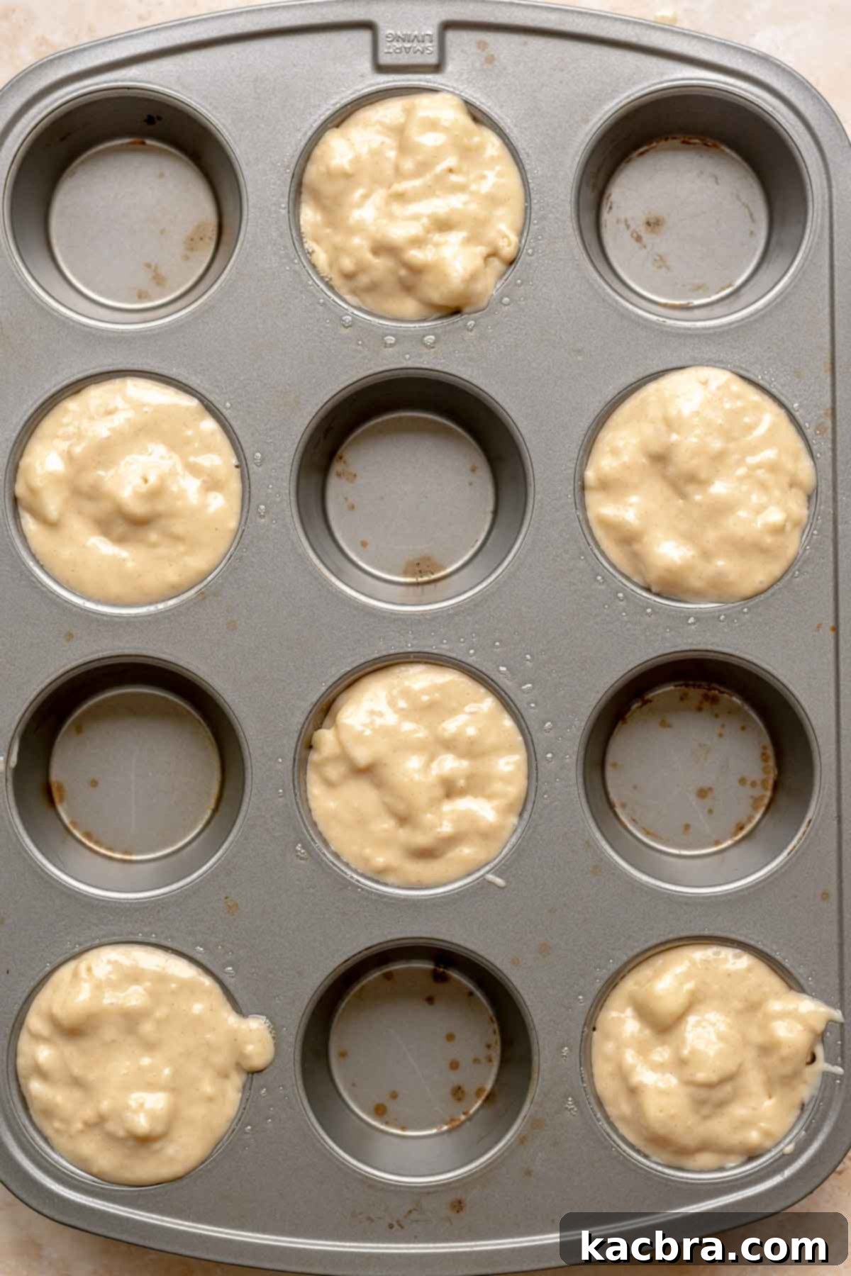 A muffin tin filled with pear muffin batter, ready for topping.