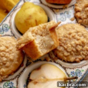 Baked pear muffins in a muffin tin. One sits in the middle with a bite removed.