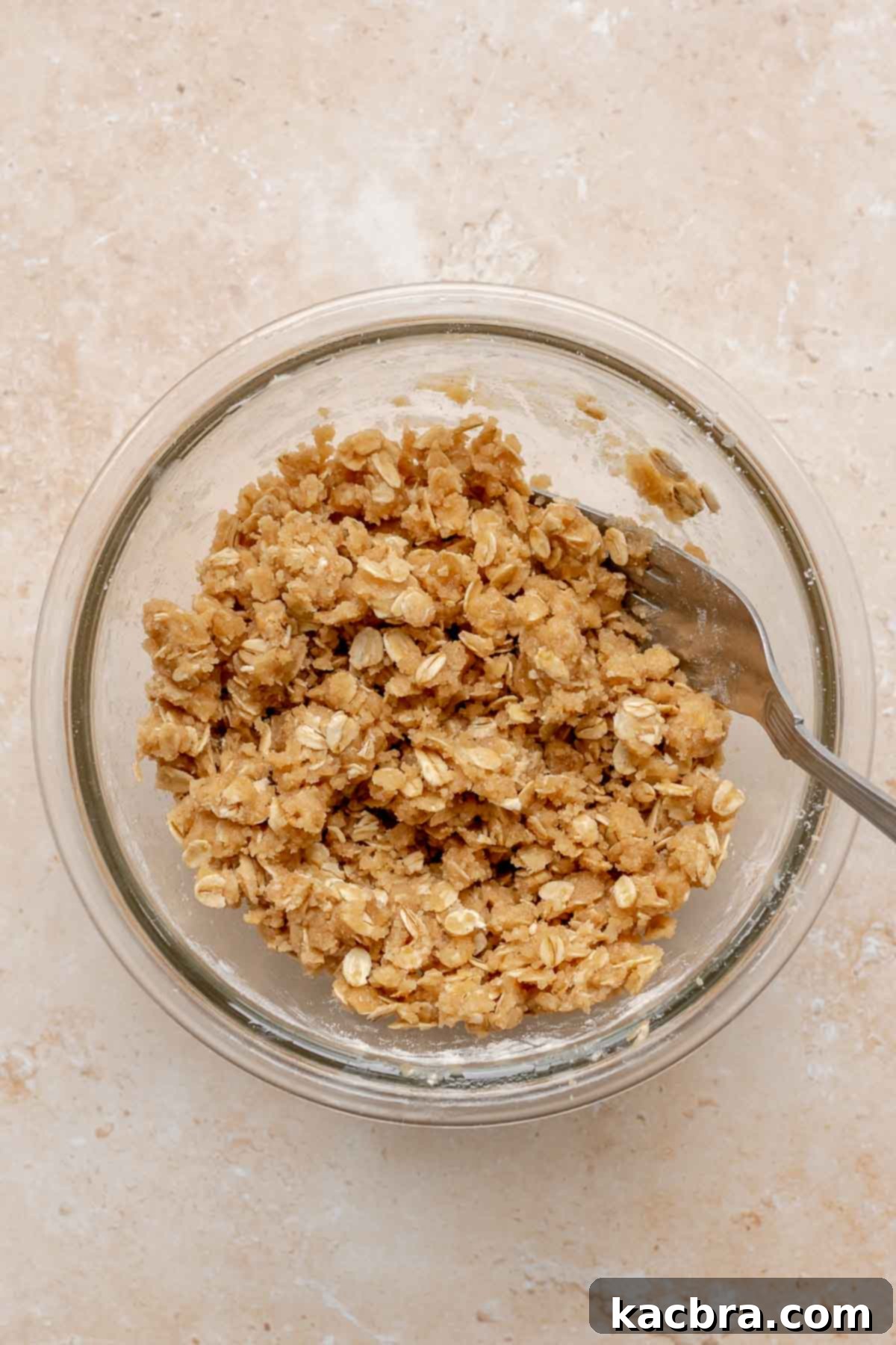 A fork mixes streusel ingredients in a mixing bowl.