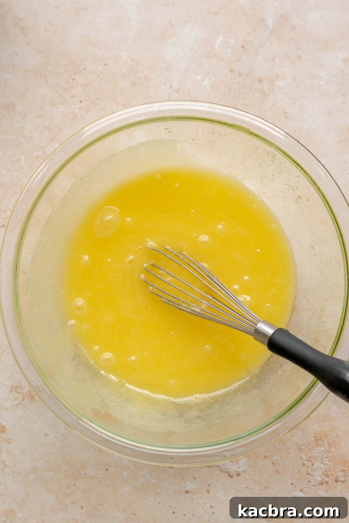 A whisk mixes wet ingredients in a bowl until smooth.