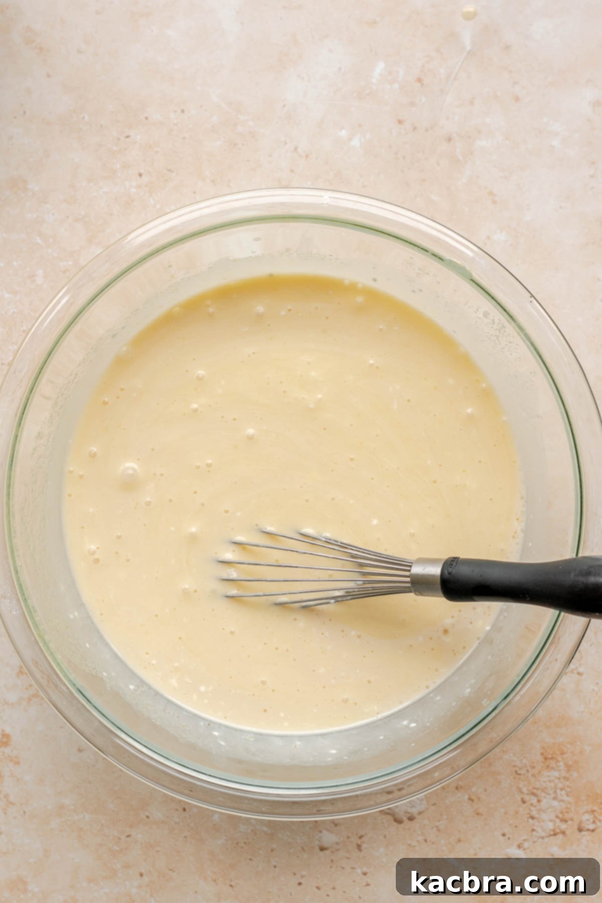 Additional wet ingredients, sour cream, milk, and vanilla, being whisked into a bowl.