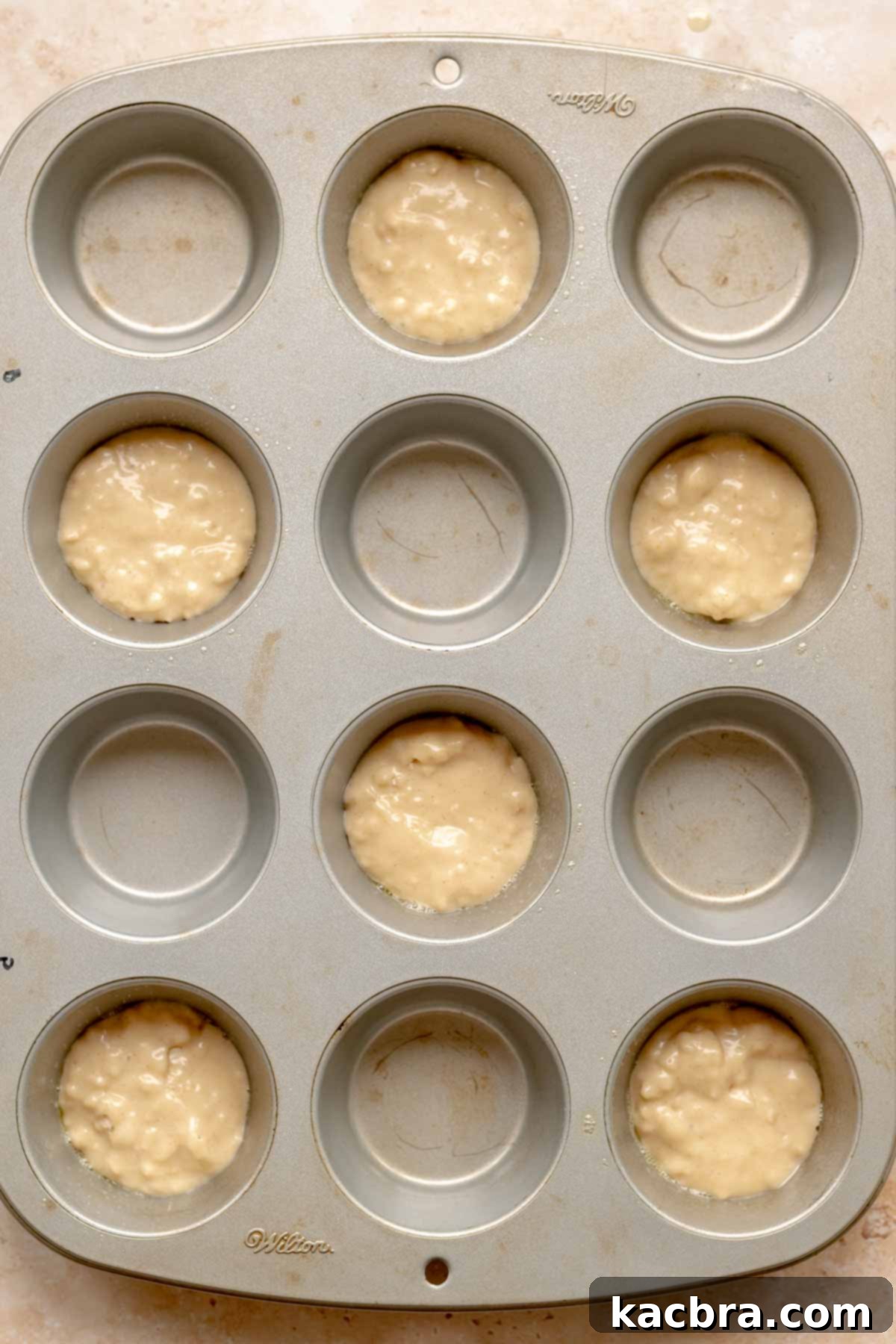 A small amount of plain batter at the bottom of a muffin tin cup.