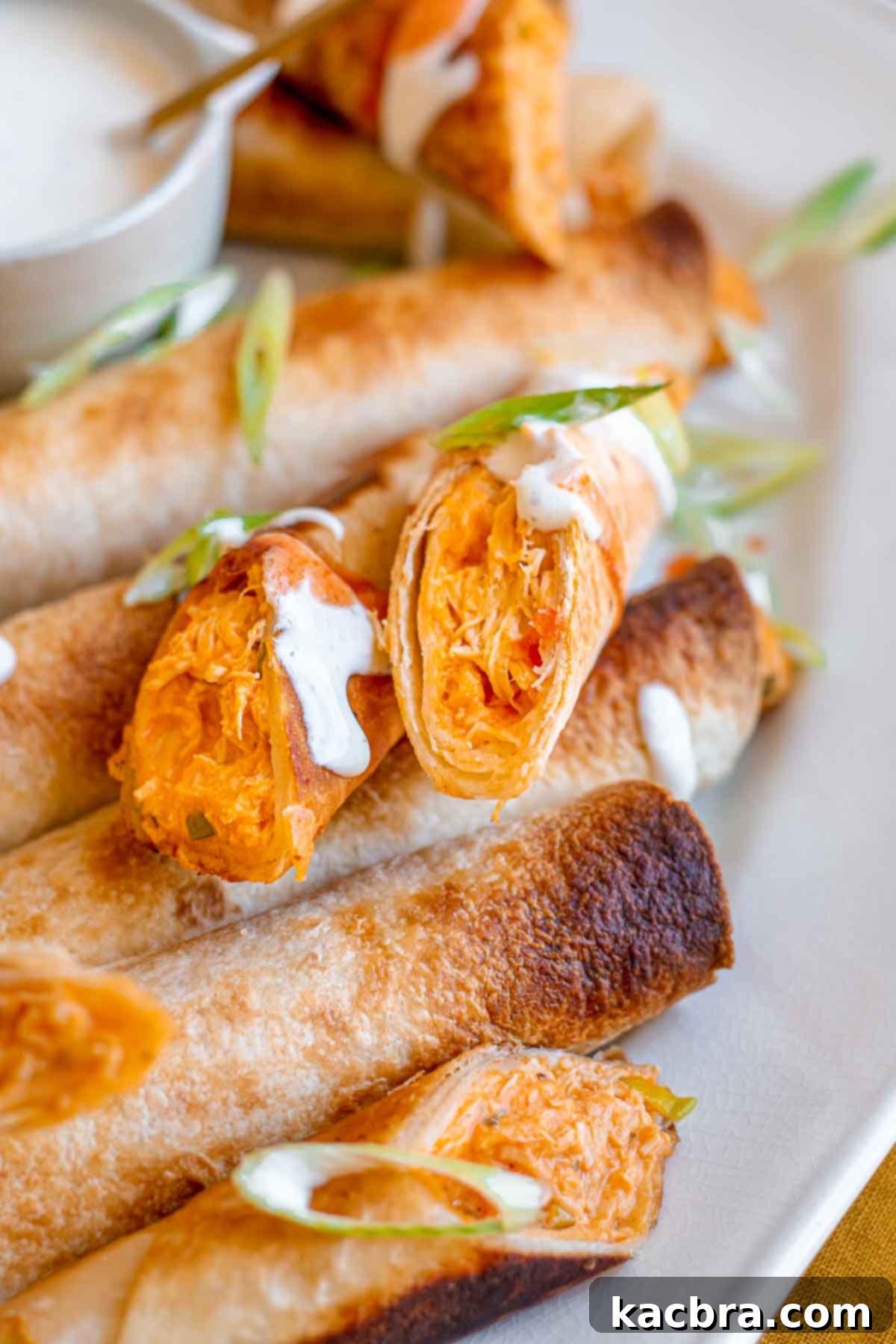 A buffalo chicken taquito sliced in half, revealing the cheesy chicken filling.