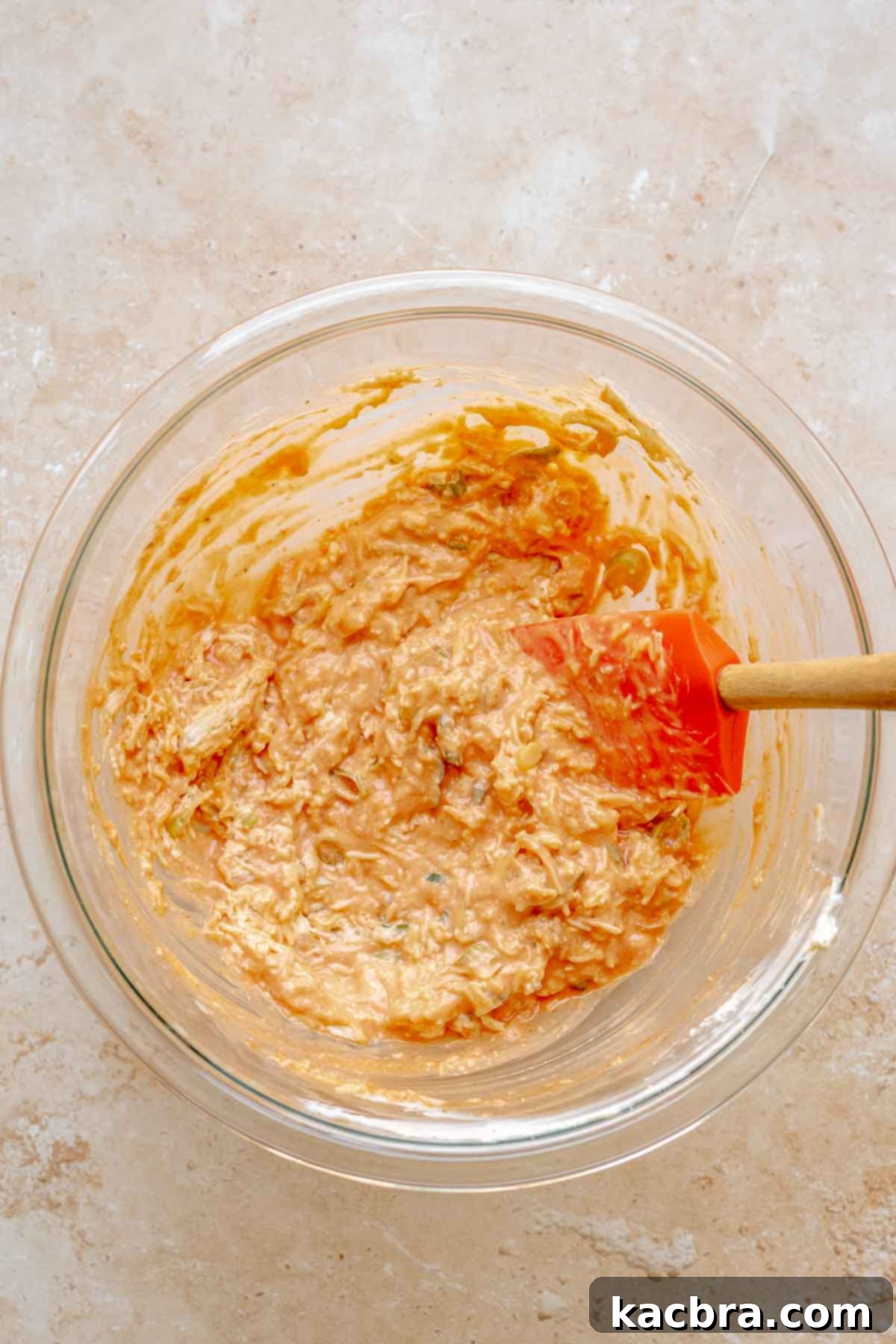 Buffalo chicken dip ingredients, including hot sauce, scallions, and mozzarella, being mixed into the cream cheese base.