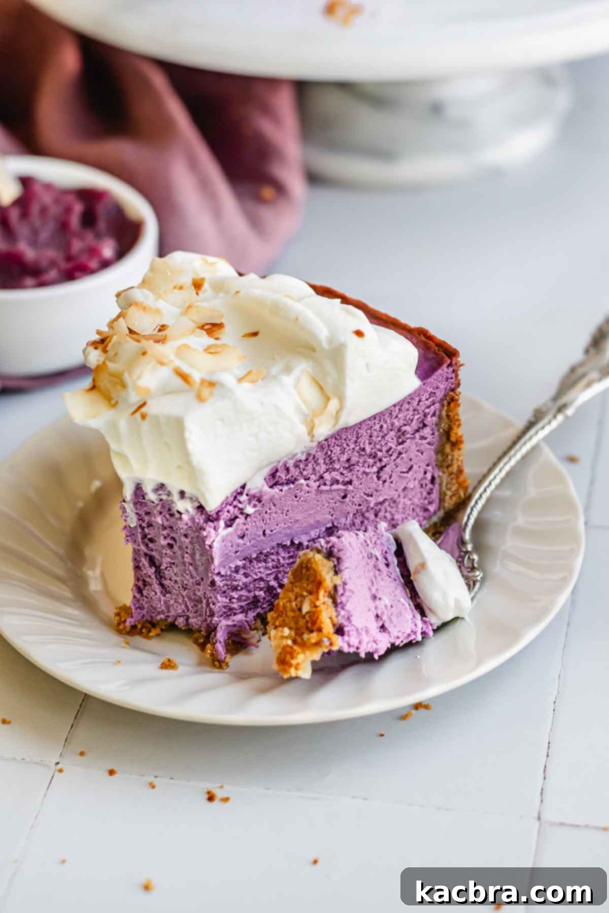 A fork with a piece of ube cheesecake on a plate.