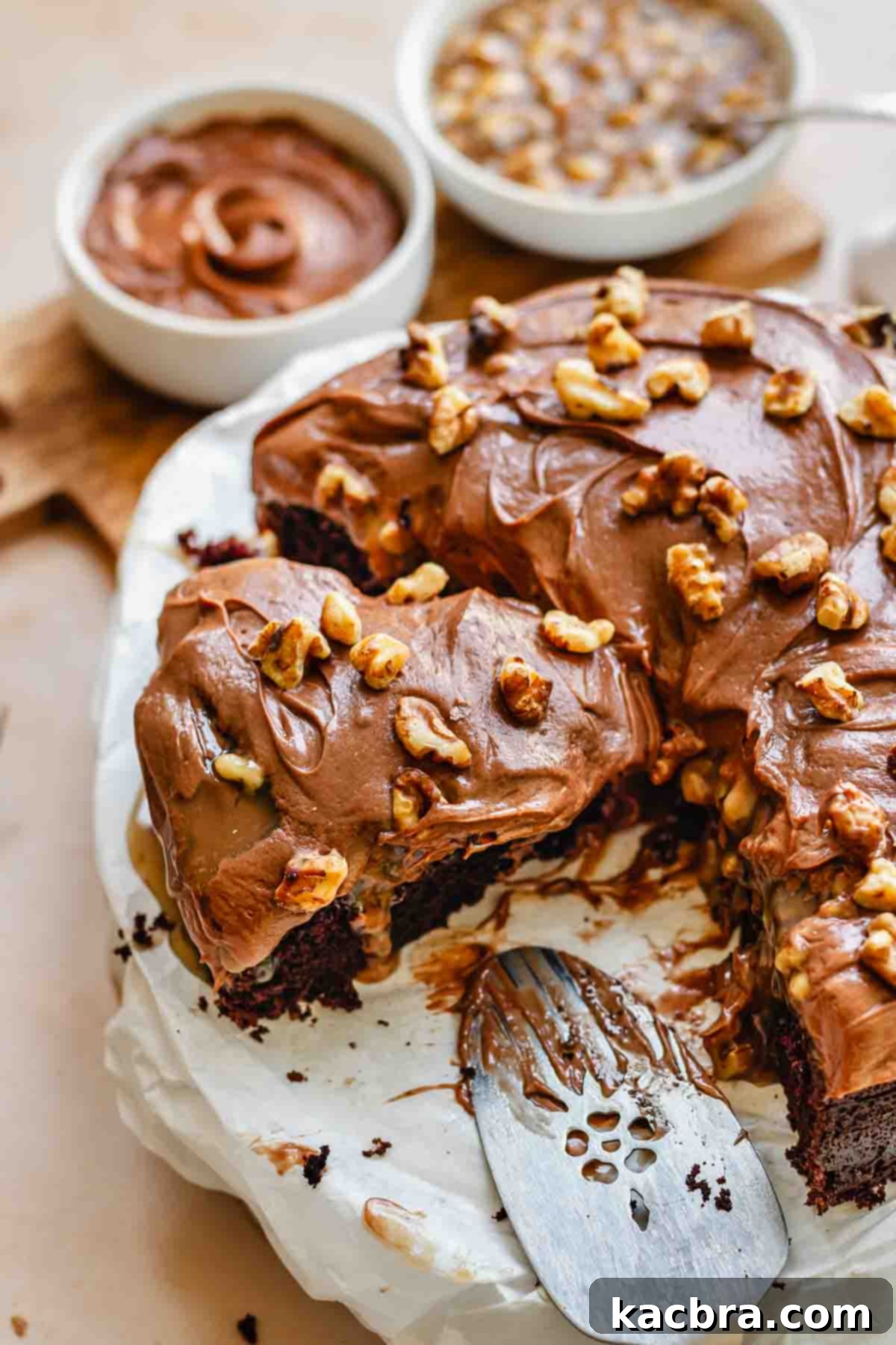Sliced chocolate walnut cake on a platter, revealing moist layers, caramel, and nuts.