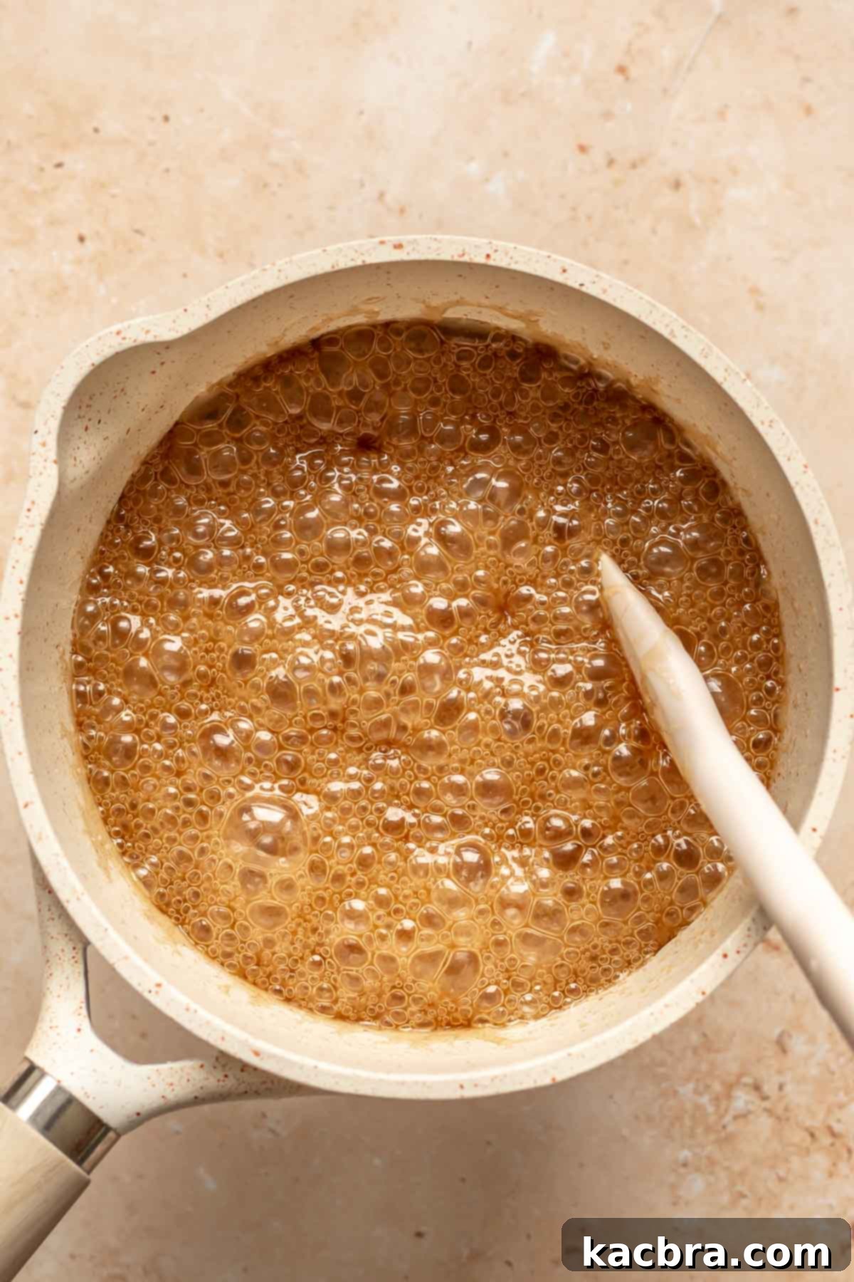 Decadent Chocolate Walnut Dream 11 A spatula stirring a bubbling caramel sauce in a saucepan on the stove, showing its glossy texture as it cooks.