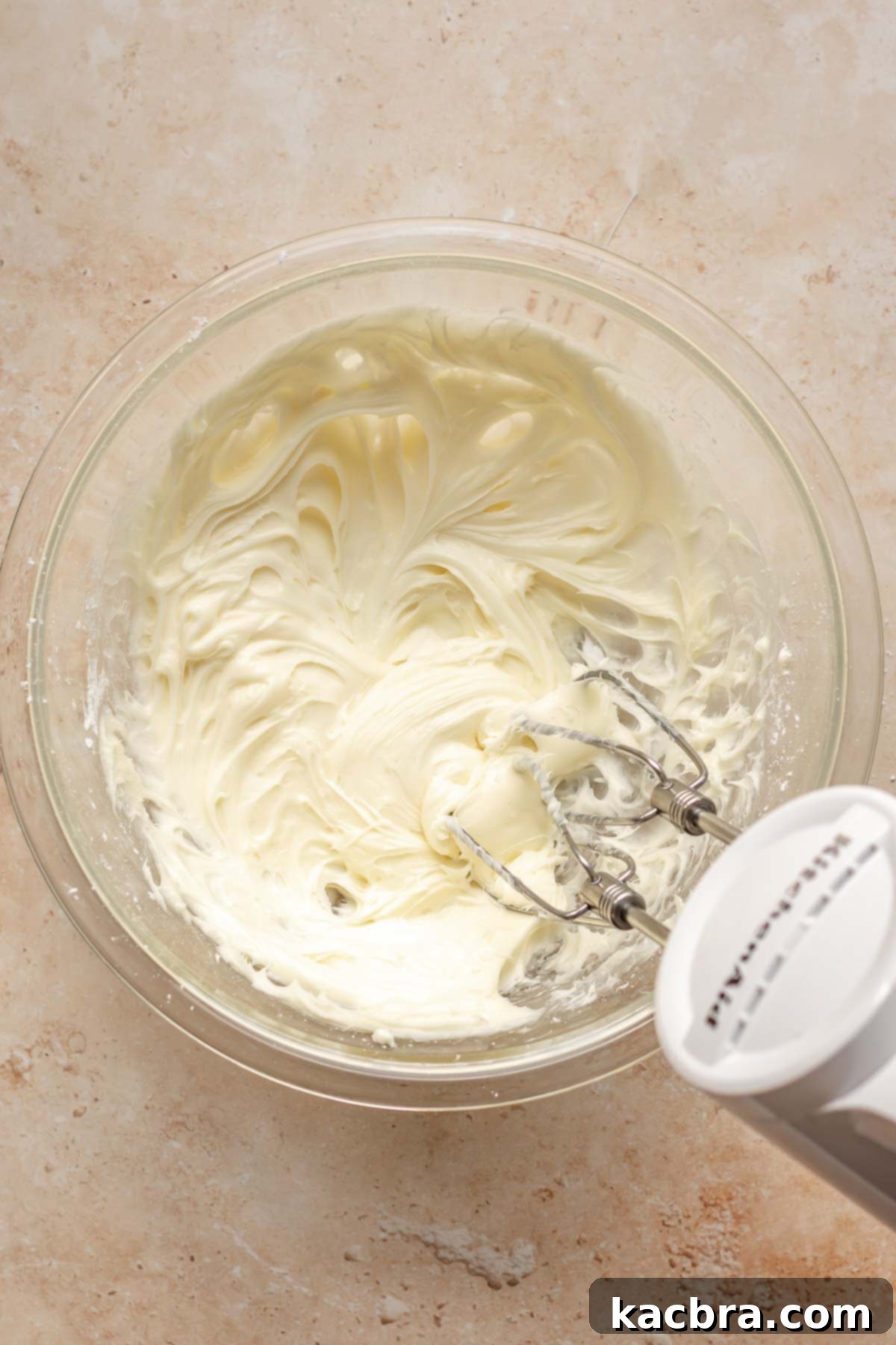 Decadent Chocolate Walnut Dream 13 A hand mixer blending cream cheese, butter, and powdered sugar in a bowl, creating the smooth base for the chocolate frosting.