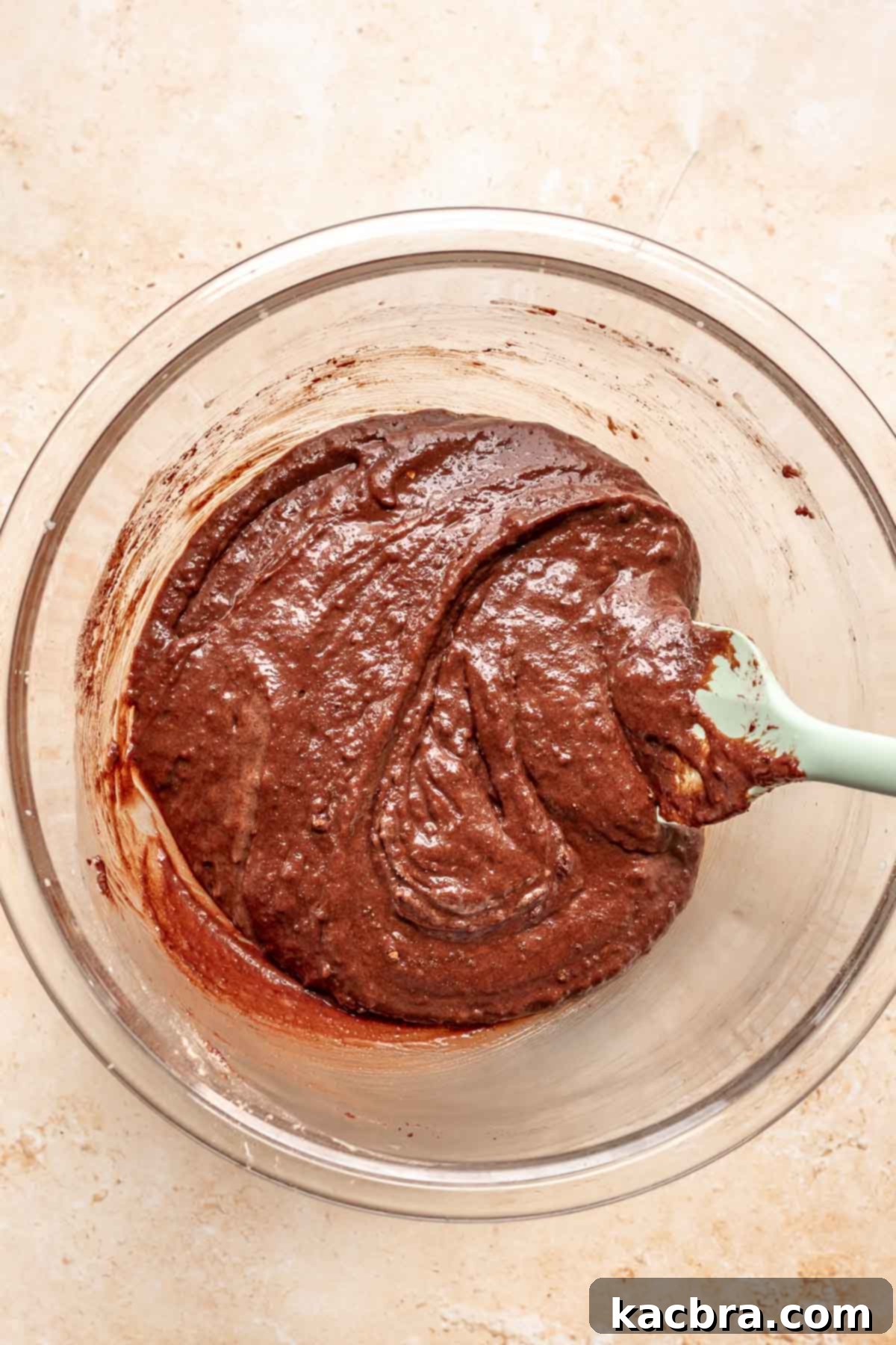 Decadent Chocolate Walnut Dream 8 A rubber spatula gently folds together chocolate cake batter in a bowl, showing its thick consistency before the final liquid is added.
