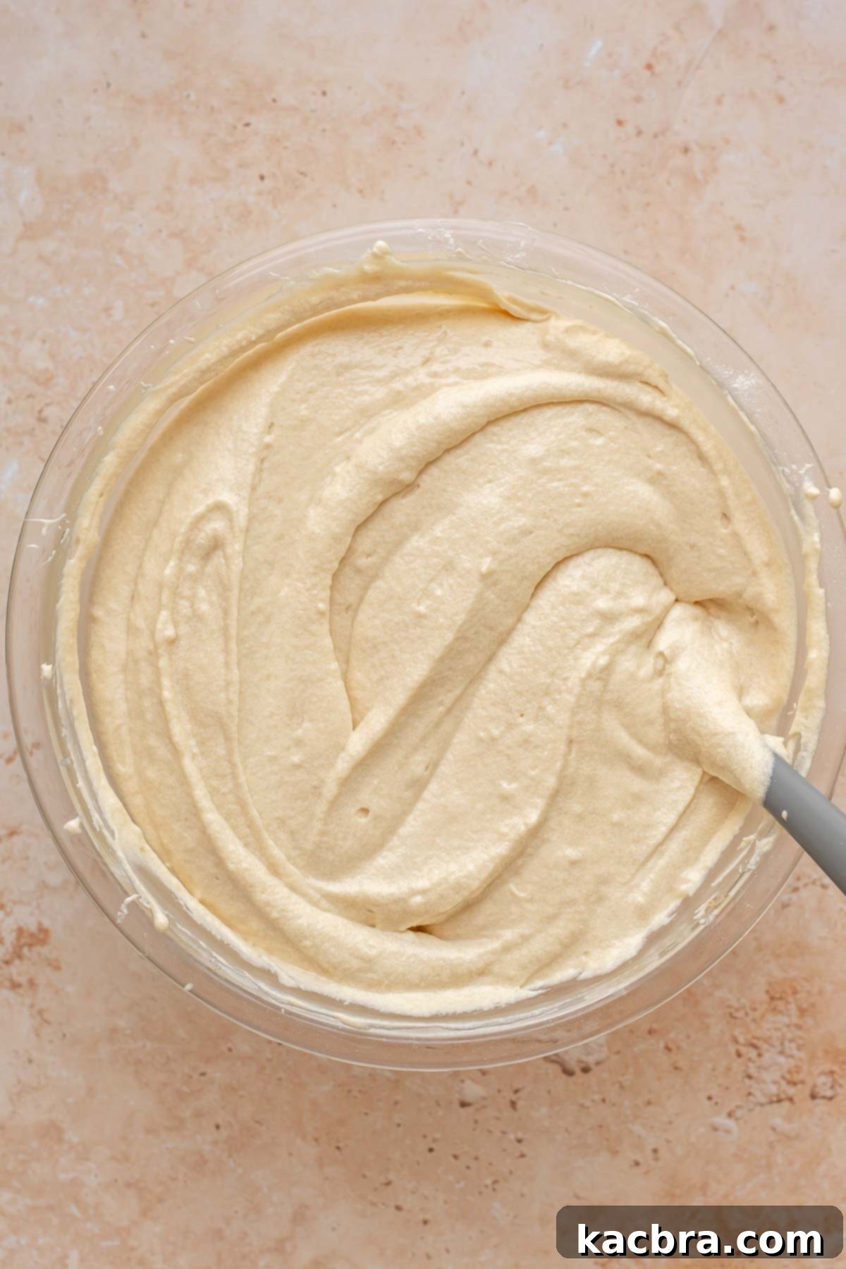 Finished vanilla cake batter with a rubber spatula in the bowl.