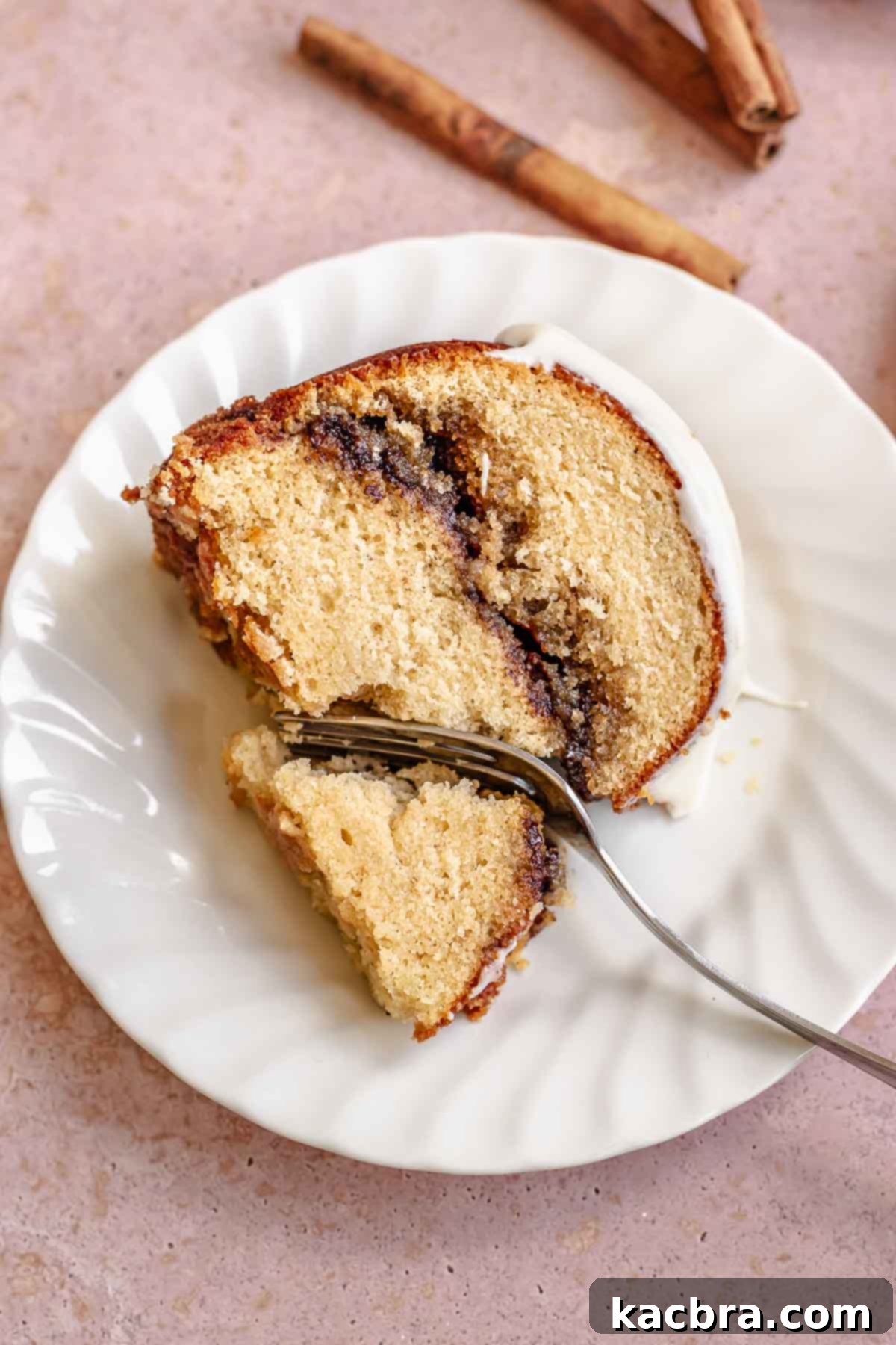 A piece of cinnamon bundt cake on a plate with a fork cutting into it.