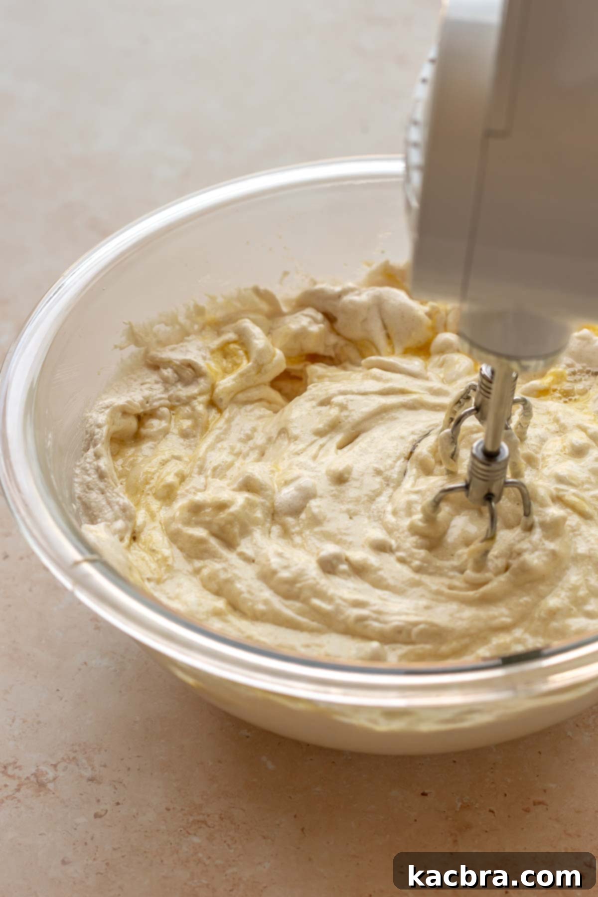 A hand mixer mixes vanilla cake batter.
