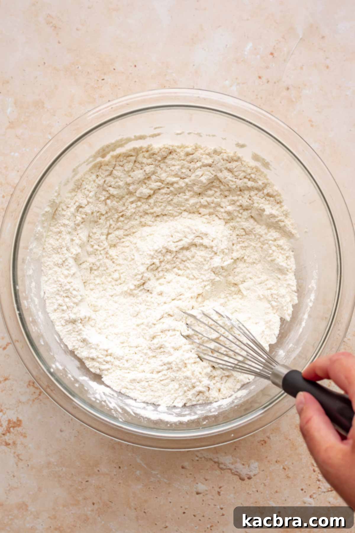 A hand whisks together dry ingredients in a bowl.