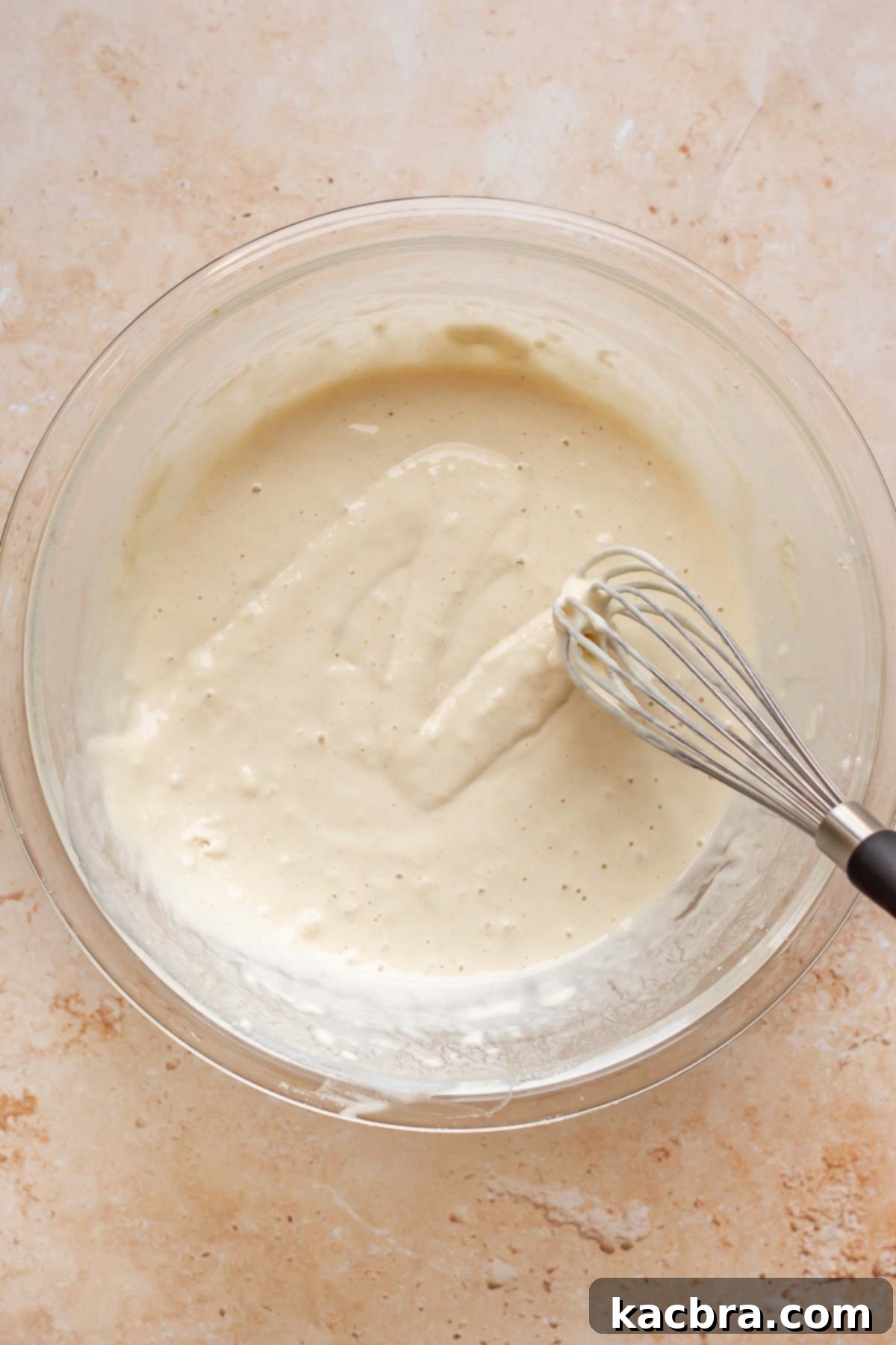 A whisk ribbons fry batter in a bowl.