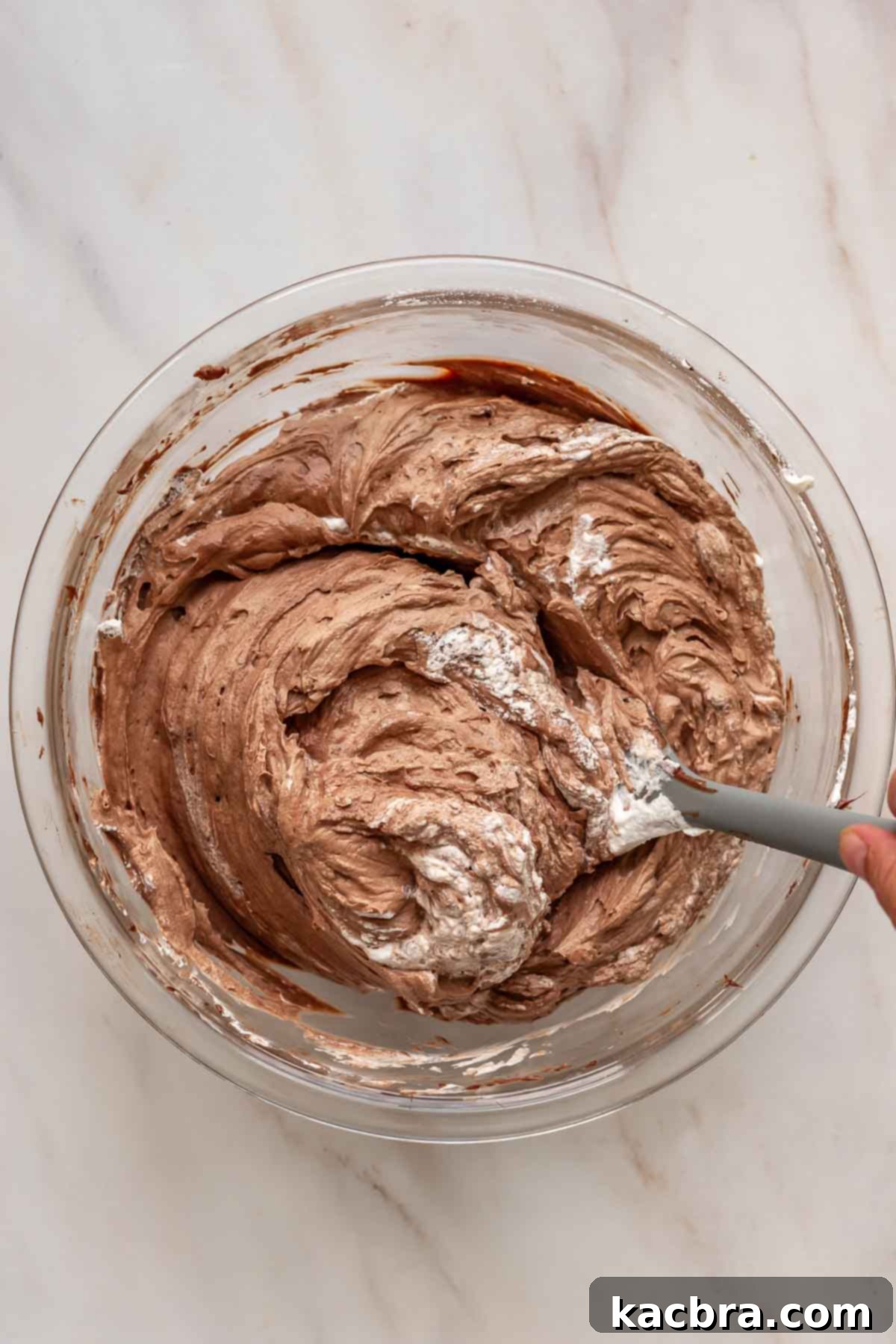 No-Bake Chocolate Orange Velvet Cheesecake 12 A rubber spatula folds whipped cream into chocolate cheesecake batter.