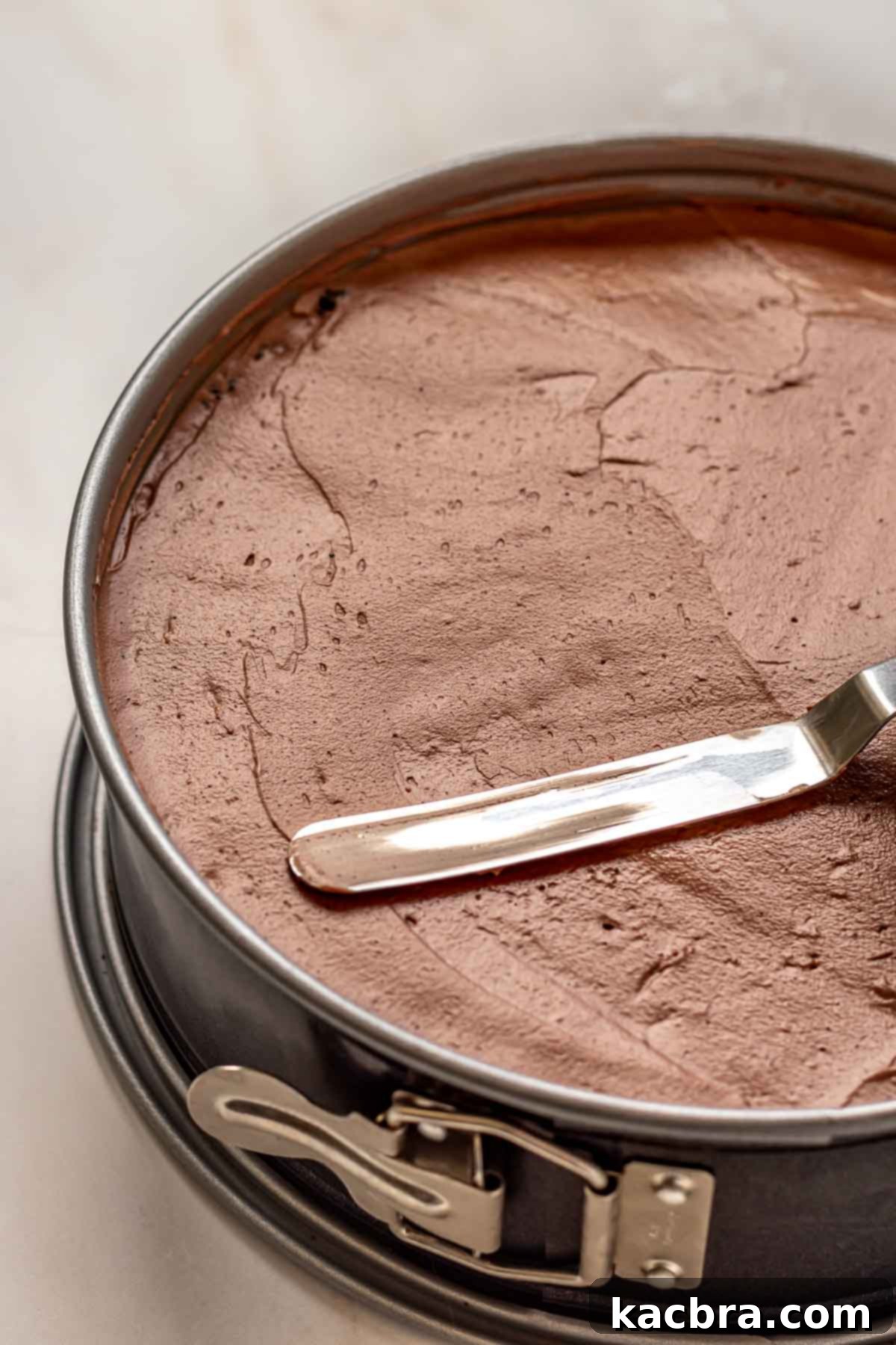 No-Bake Chocolate Orange Velvet Cheesecake 13 An offset spatula smooths chocolate orange cheesecake batter into a springform pan.