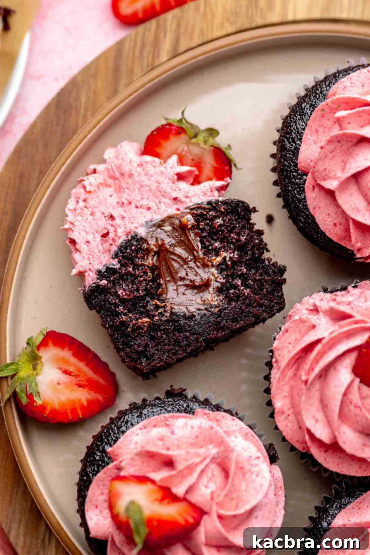Chocolate strawberry cupcake cut open on a plate to show the chocolate filling.