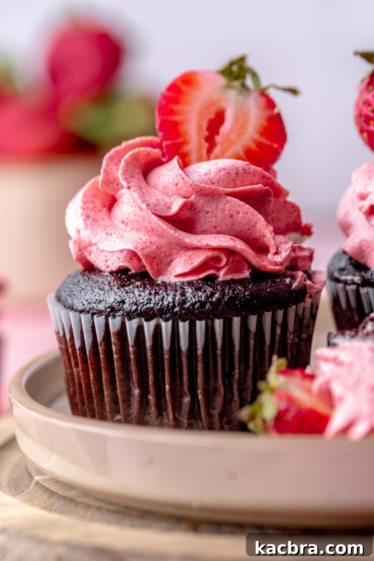 Frosted chocolate strawberry cupcake with a strawberry on top.