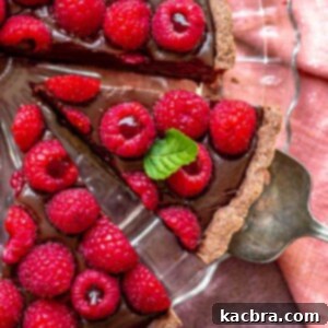Decadent Chocolate Raspberry Delight 12 A serving utensil removes a slice of chocolate raspberry tart from a platter.