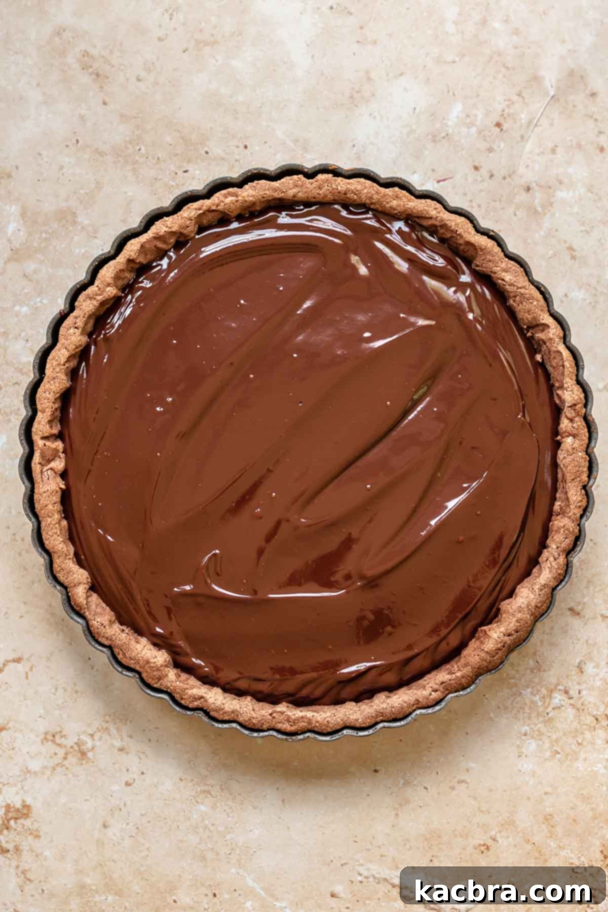 Smooth dark chocolate ganache spread evenly into a tart shell.