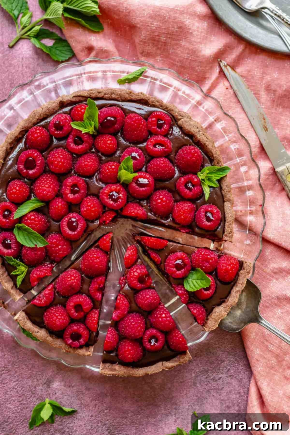 A beautifully sliced chocolate raspberry tart on a platter, ready to be served.