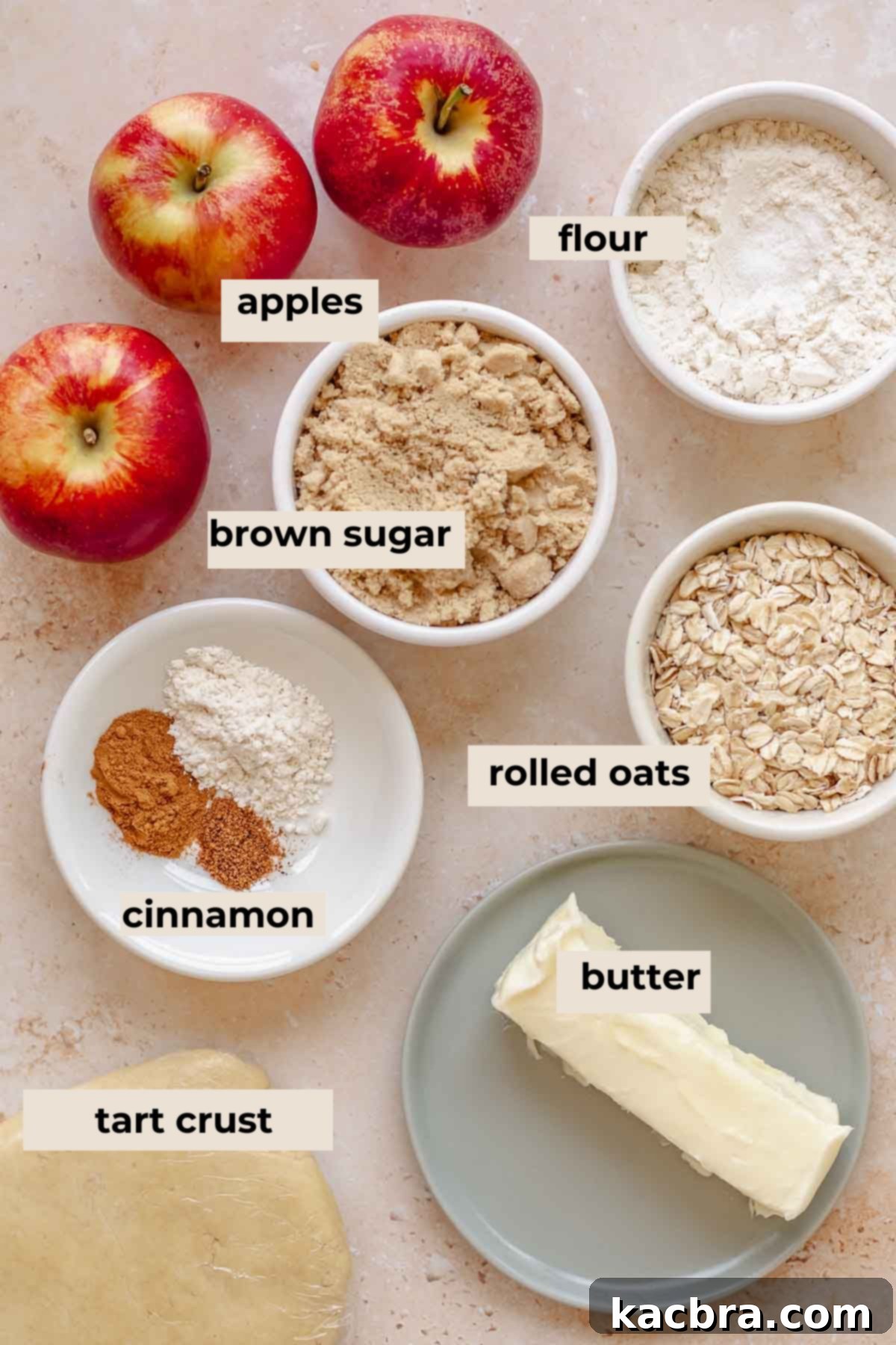 Cinnamon Apple Crumble Tart 3 A collection of fresh ingredients laid out on a table, including apples, oats, brown sugar, butter, flour, and spices, ready for making an apple crumble tart.