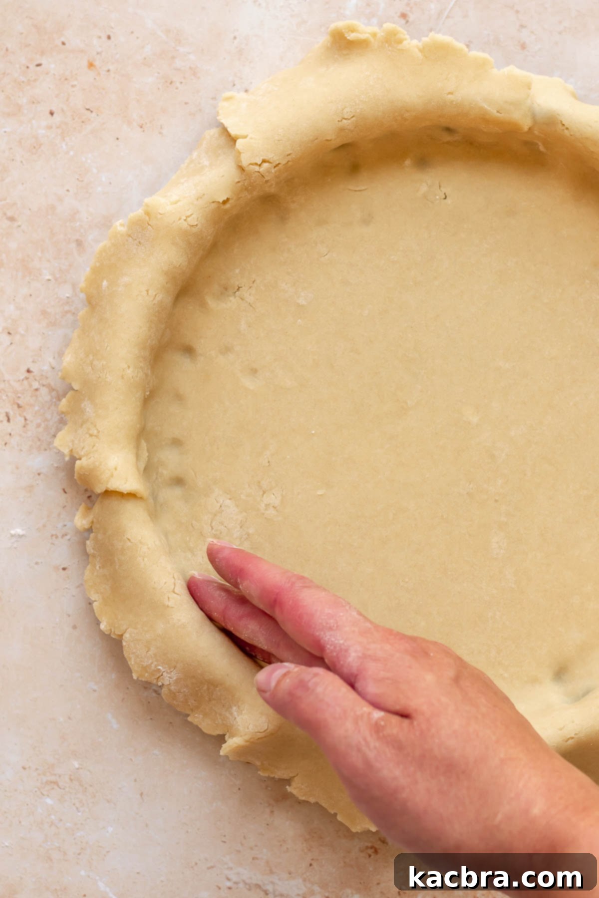 Cinnamon Apple Crumble Tart 5 A hand gently presses sweet tart dough into the fluted edges and bottom of a tart pan, ensuring a snug fit for the crust.