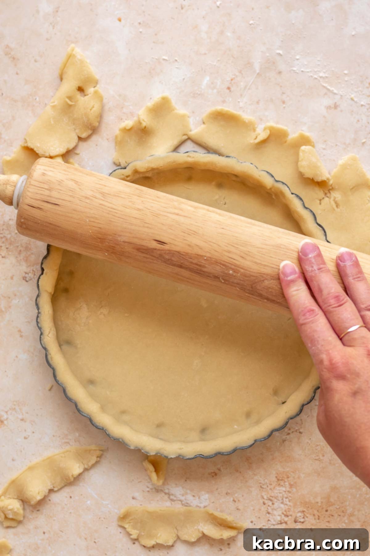 Cinnamon Apple Crumble Tart 6 A rolling pin is used to roll over the top edge of a tart pan, neatly trimming away excess pastry dough for a clean finish.