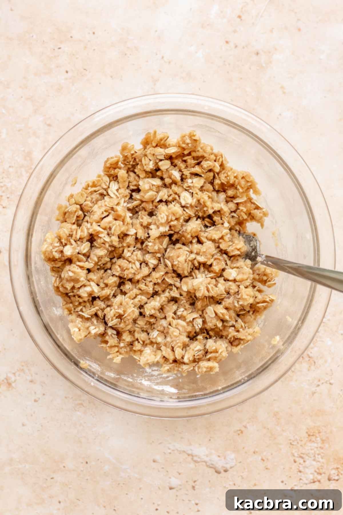 Cinnamon Apple Crumble Tart 7 A fork is mixing together ingredients for a crumble topping in a ceramic bowl, forming small to medium-sized buttery crumbles.