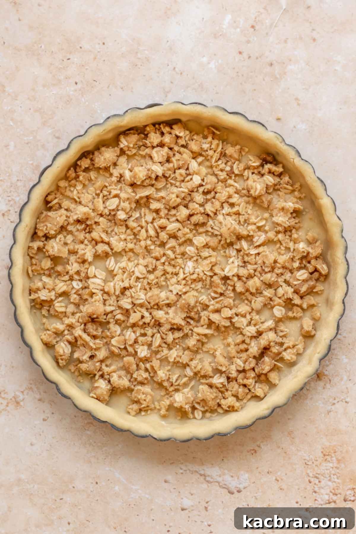 Cinnamon Apple Crumble Tart 8 A generous layer of crumble topping is sprinkled over the bottom of a tart dough shell, forming the first layer of the apple crumble tart.