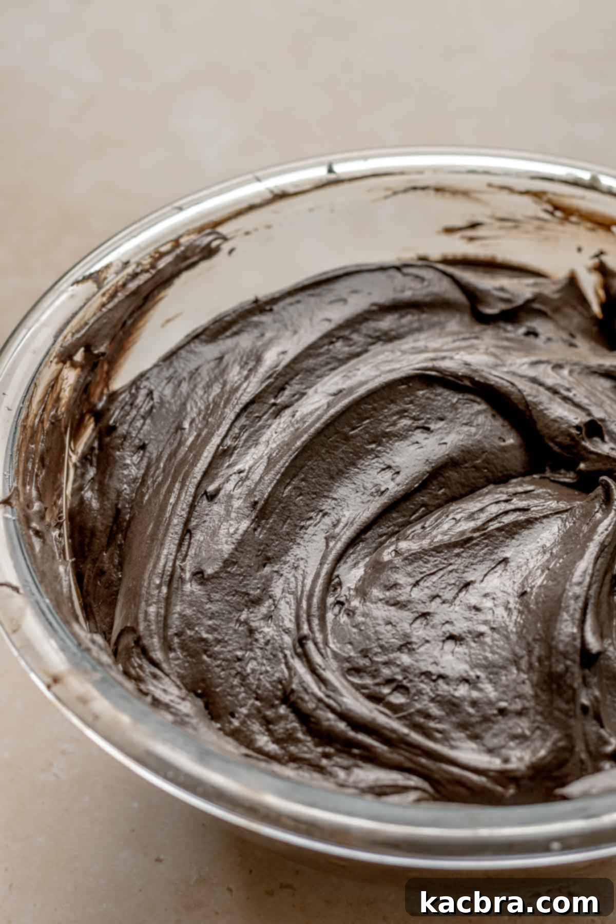 A spatula gently folding whipped cream into the dark chocolate cheesecake batter.