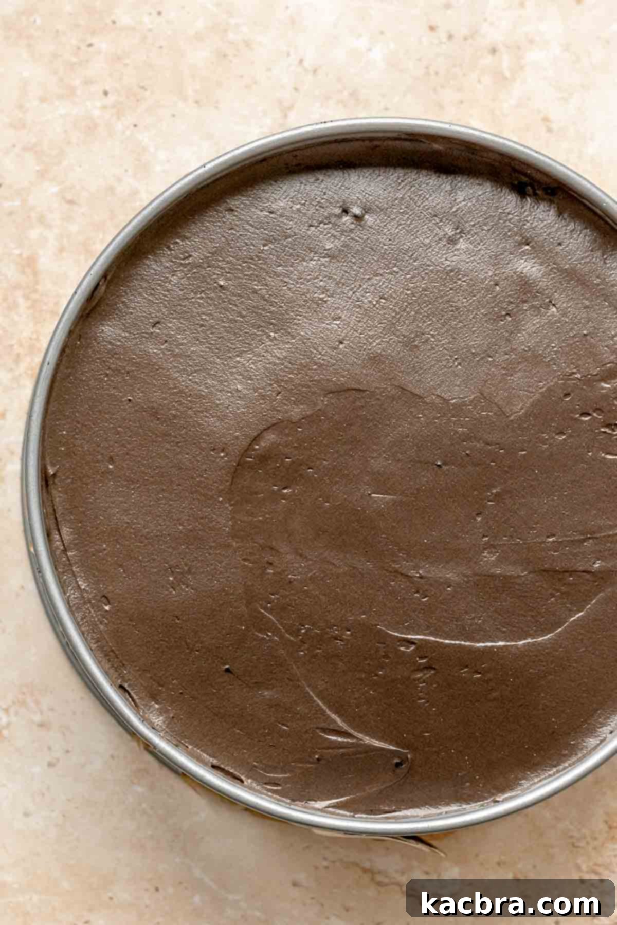 Smoothed chocolate cheesecake batter in a springform pan.
