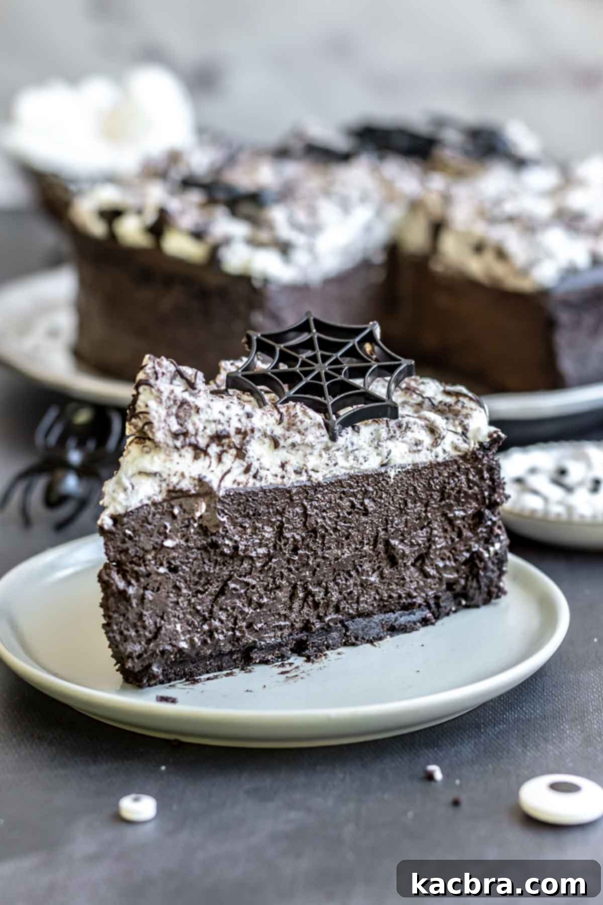 A slice of dark chocolate Halloween cheesecake on a plate, adorned with a delicate white chocolate spider web design.