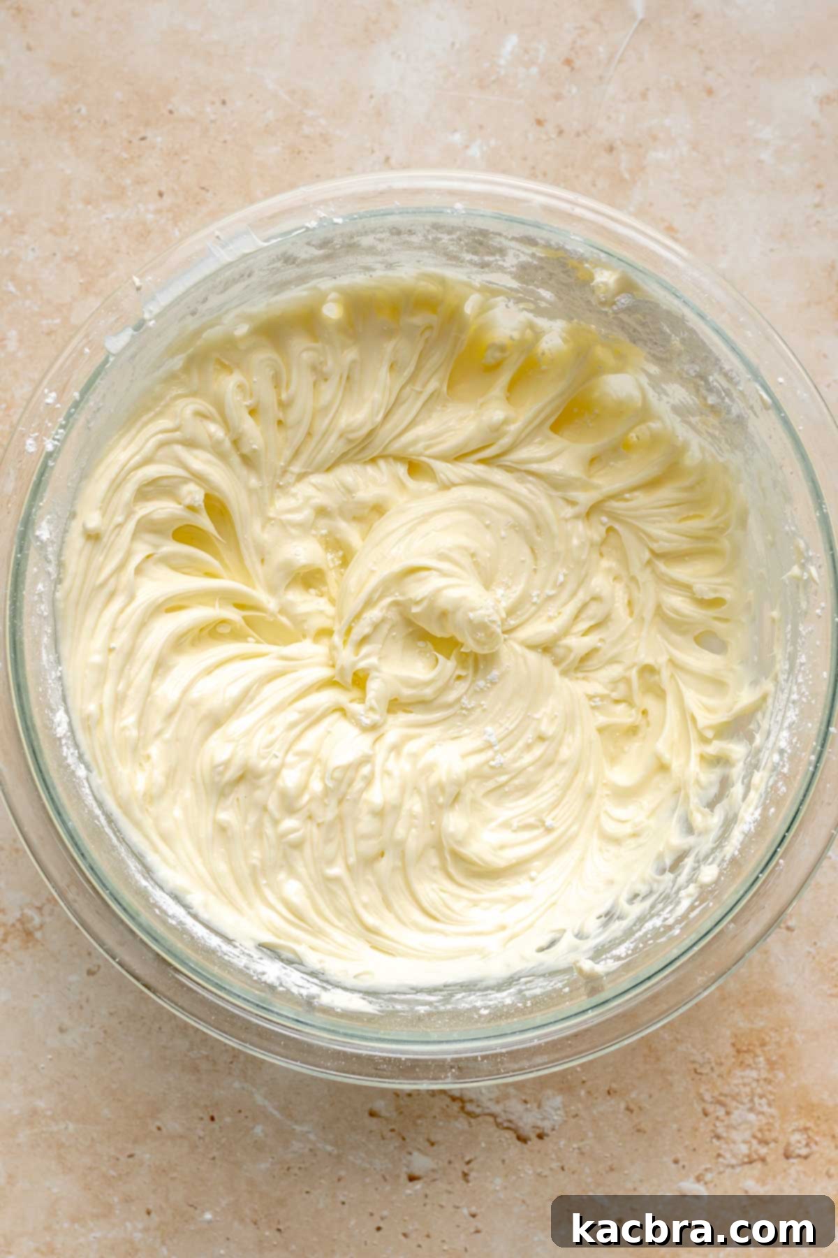 Creamed cheesecake batter in a mixing bowl after cream cheese and sugar have been combined.