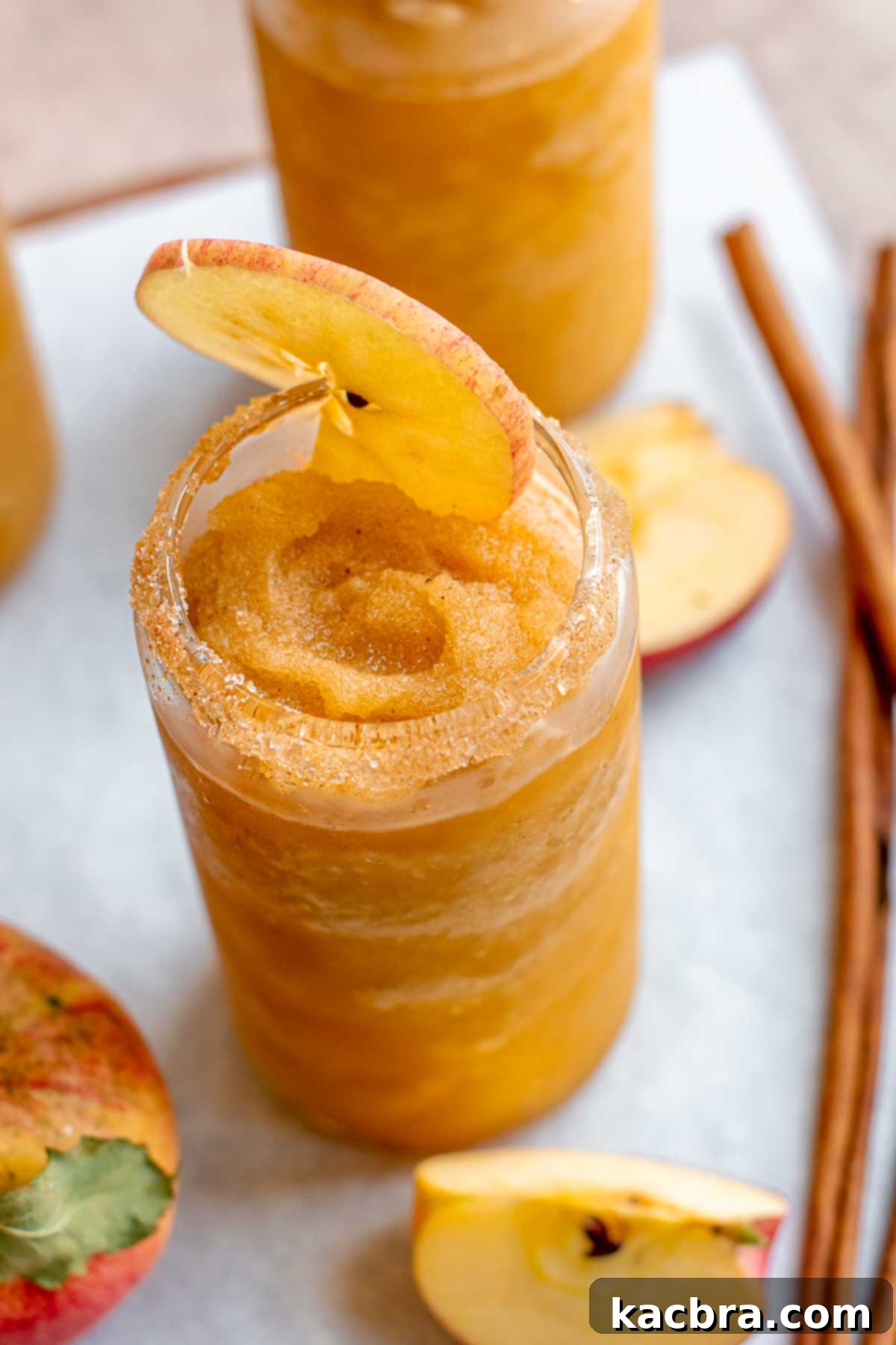 Spiced Apple Slush: Customize Your Cool 12 Apple cider slushie in a glass with a slice of apple in the top.