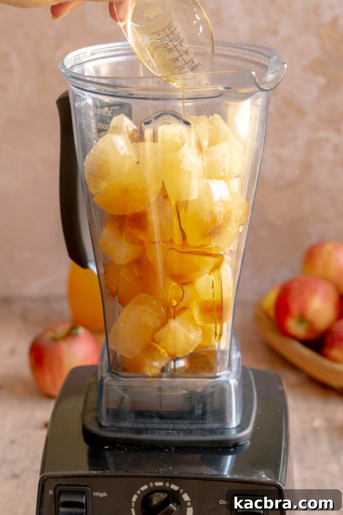 Spiced Apple Slush: Customize Your Cool 8 A hand pours maple syrup into a blender full of apple cider ice cubes.