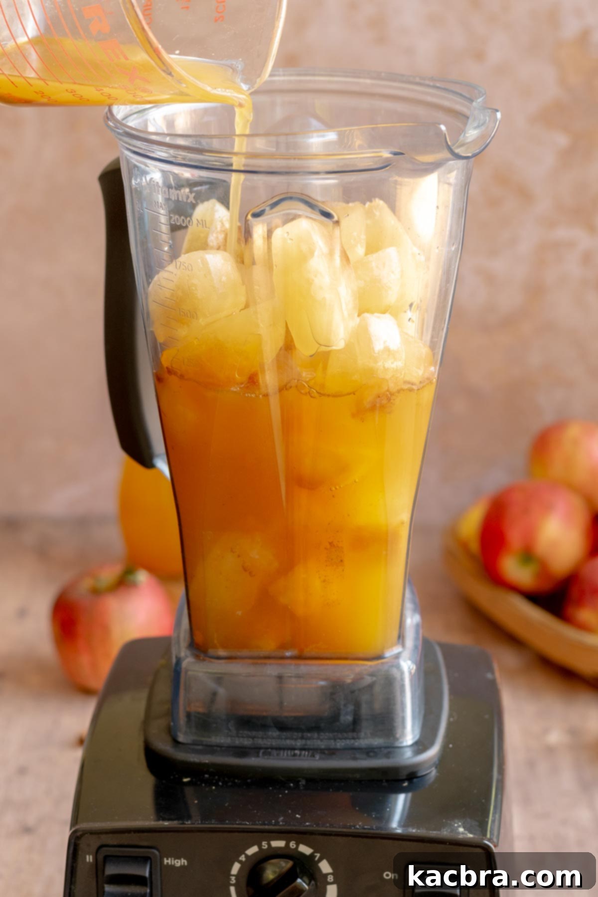 Spiced Apple Slush: Customize Your Cool 9 A hand pours apple cider over apple cider ice cubes in a blender.