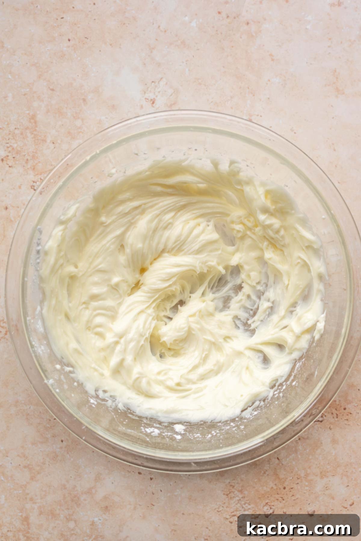 Creamy Pumpkin Cloud 6 Softened cream cheese and powdered sugar being creamed together in a mixing bowl until smooth and fluffy.