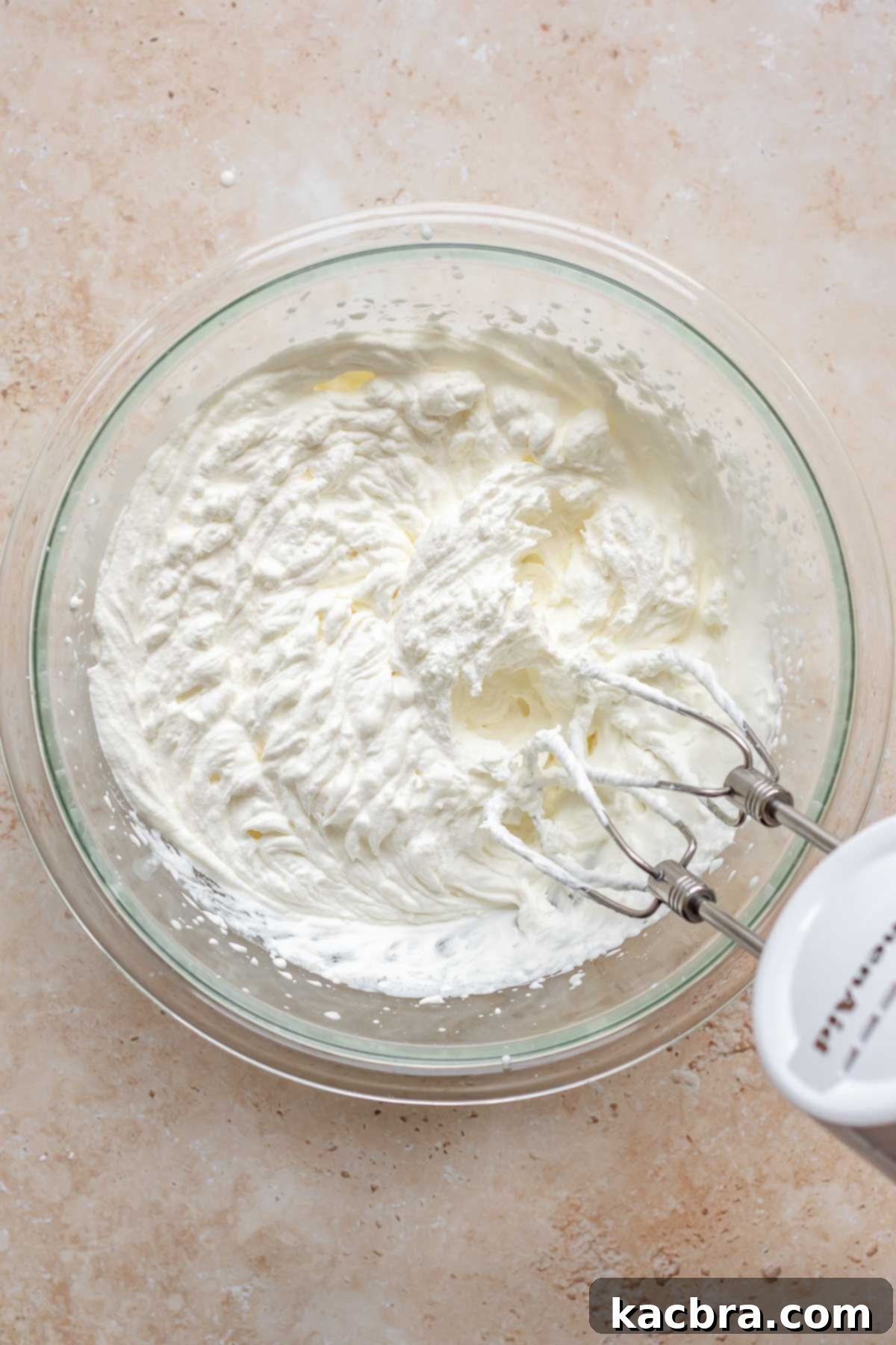 Creamy Pumpkin Cloud 8 Heavy whipping cream being whipped to stiff peaks in a separate bowl using an electric hand mixer.