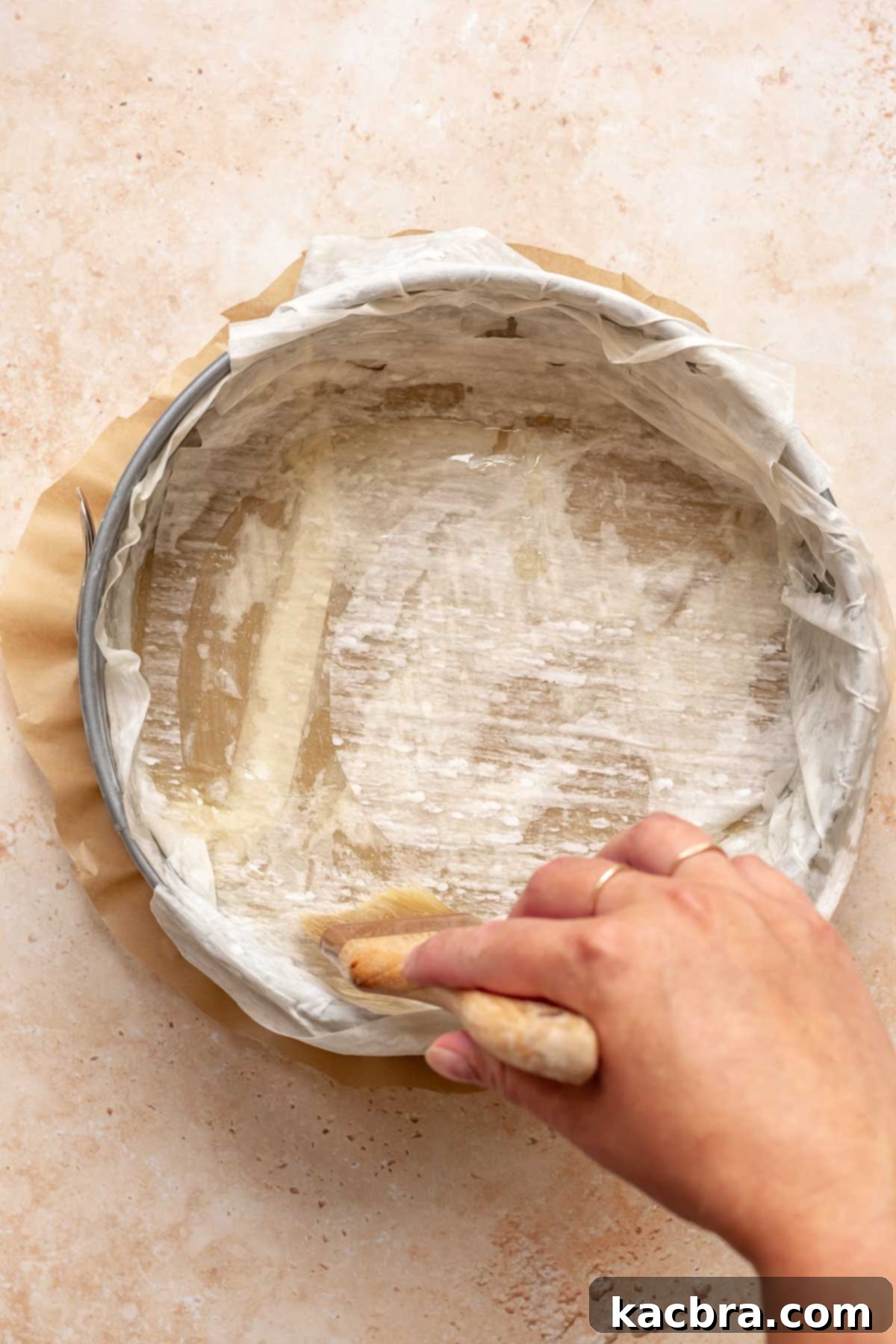 Golden Honey Baklava Dream Cake 6 A pastry brush applies melted butter to a sheet of phyllo dough in a springform pan.