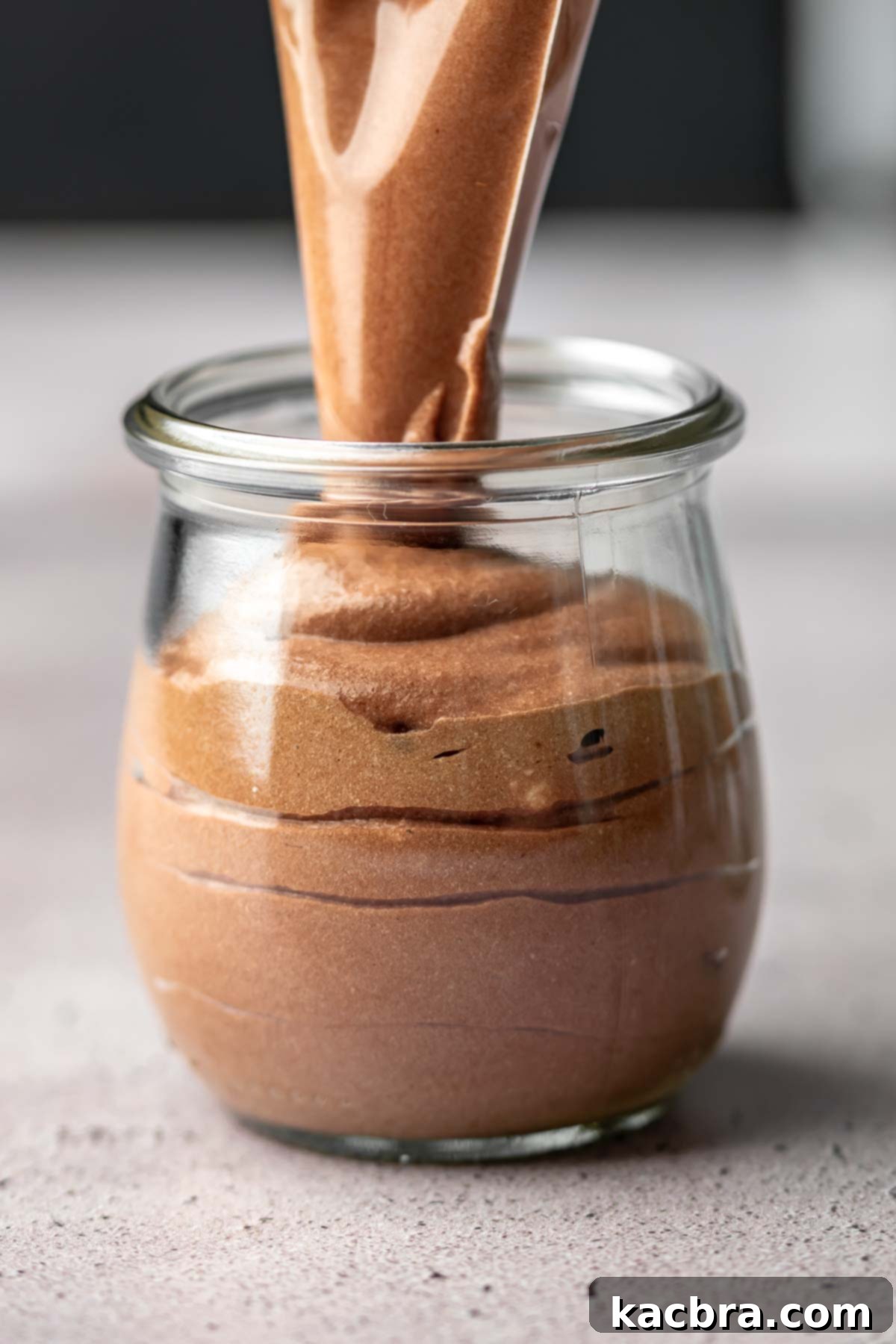 A piping bag adds chocolate Nutella mousse into a week jar.