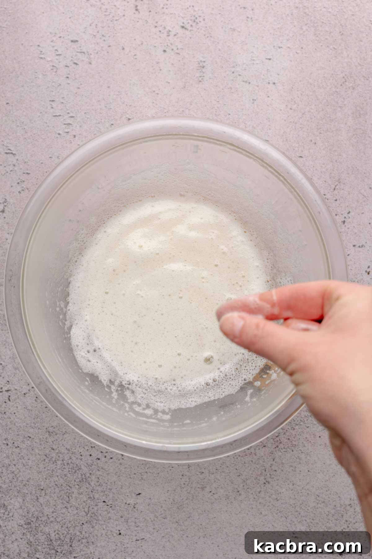A hand rubs fingers together in egg whites.