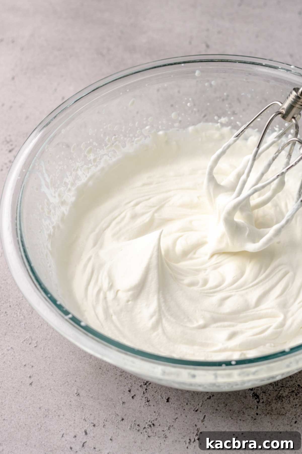 Beaters on the side of a bowl of whipped cream.