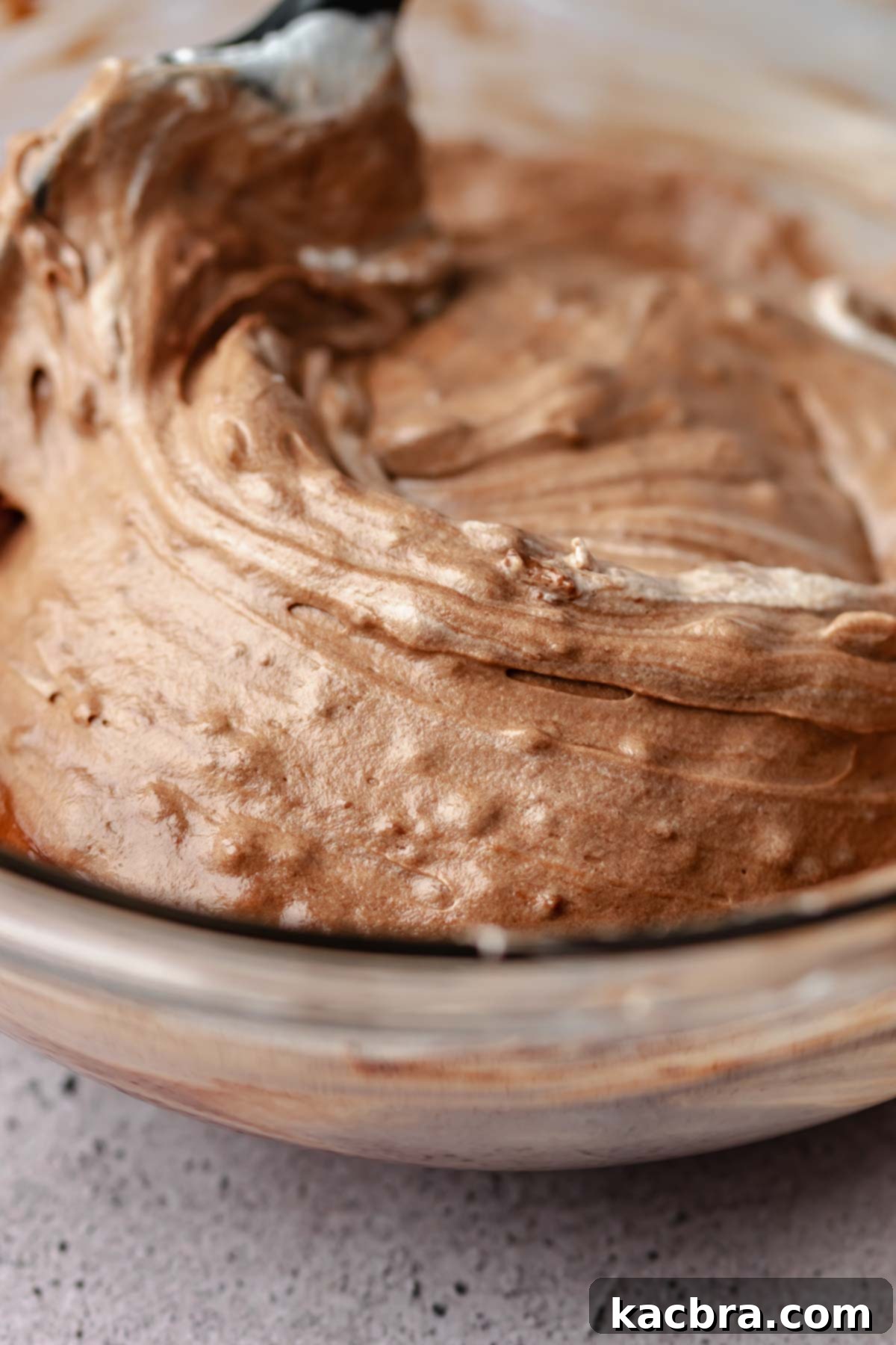 Nutella and whipped cream being mixed in a bowl.