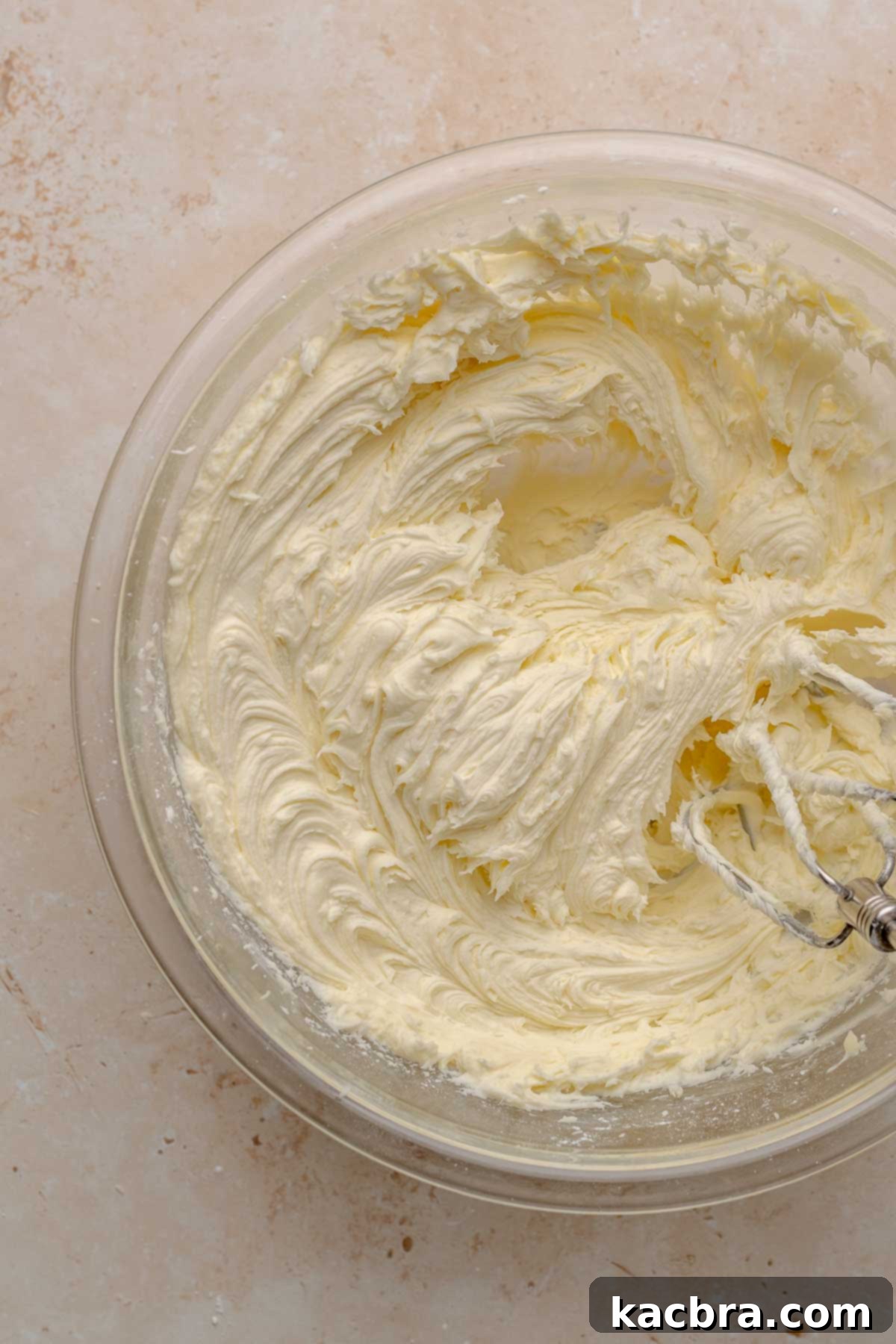 Ruby and Ivory Cupcake Delights 12 A hand mixer blends unsalted butter and powdered sugar in a bowl, forming the initial creamy base for the white chocolate frosting.