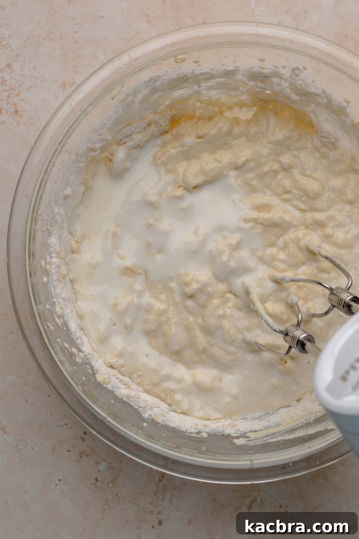 Ruby and Ivory Cupcake Delights 9 A hand mixer gently combines buttermilk into the cupcake batter in a bowl, alternating with dry ingredients for a smooth consistency.