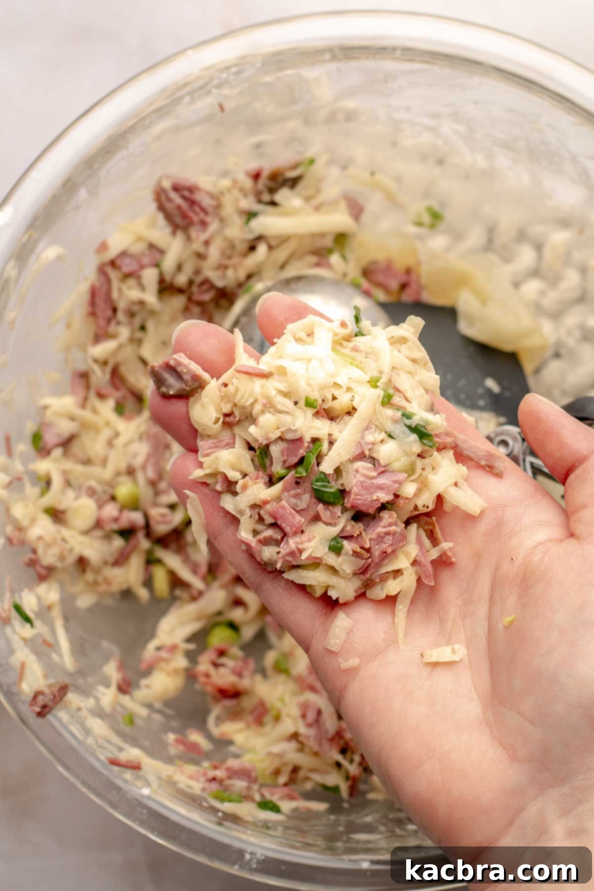 A hand holds a formed beef fritter patty.